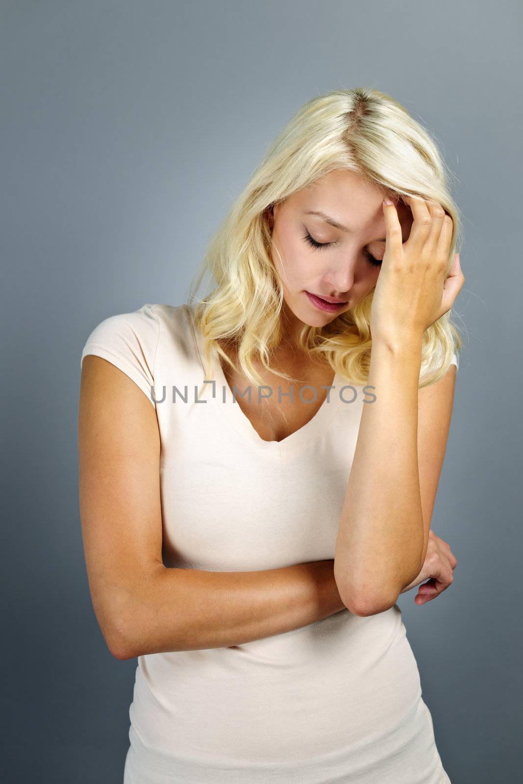 Stressed and worried young blonde woman on grey background