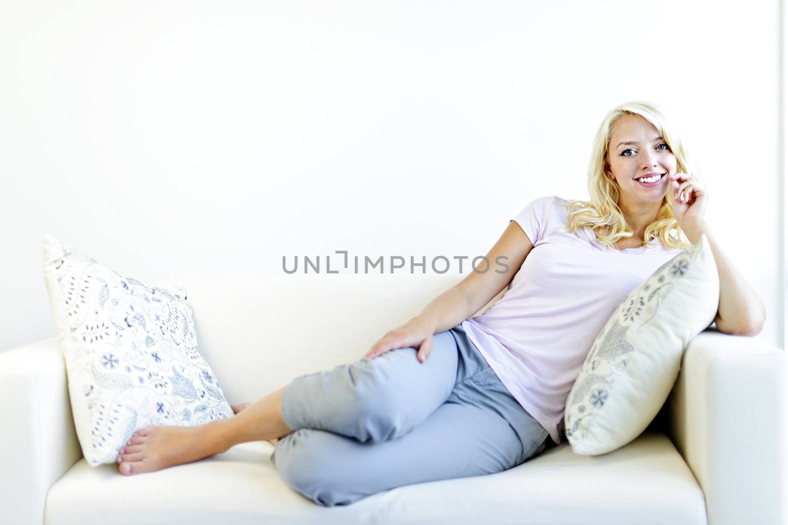 Pretty blonde woman on couch relaxing with feet up at home