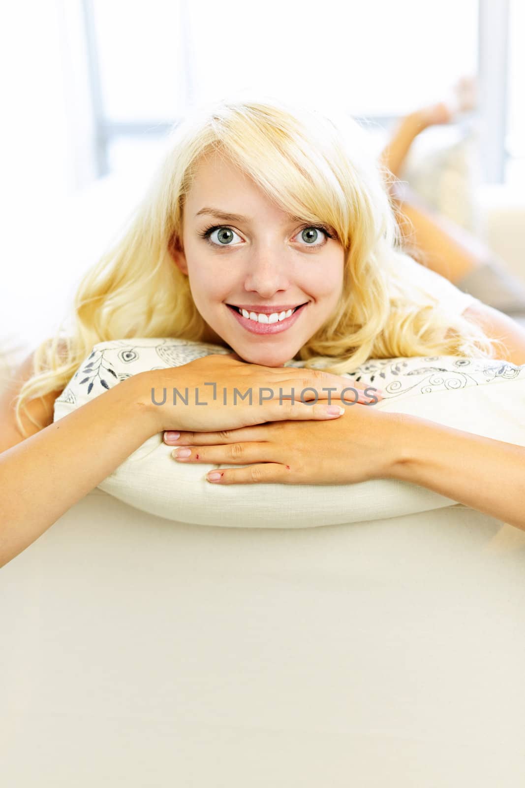 Portrait of smiling happy blonde woman relaxing on couch at home