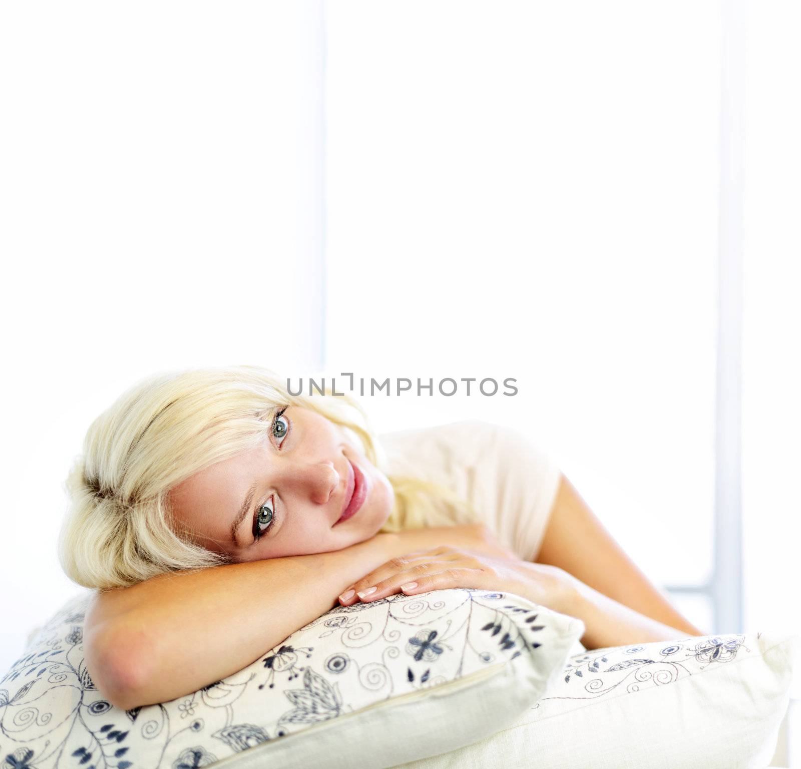 Portrait of happy blonde woman daydreaming and smiling on couch