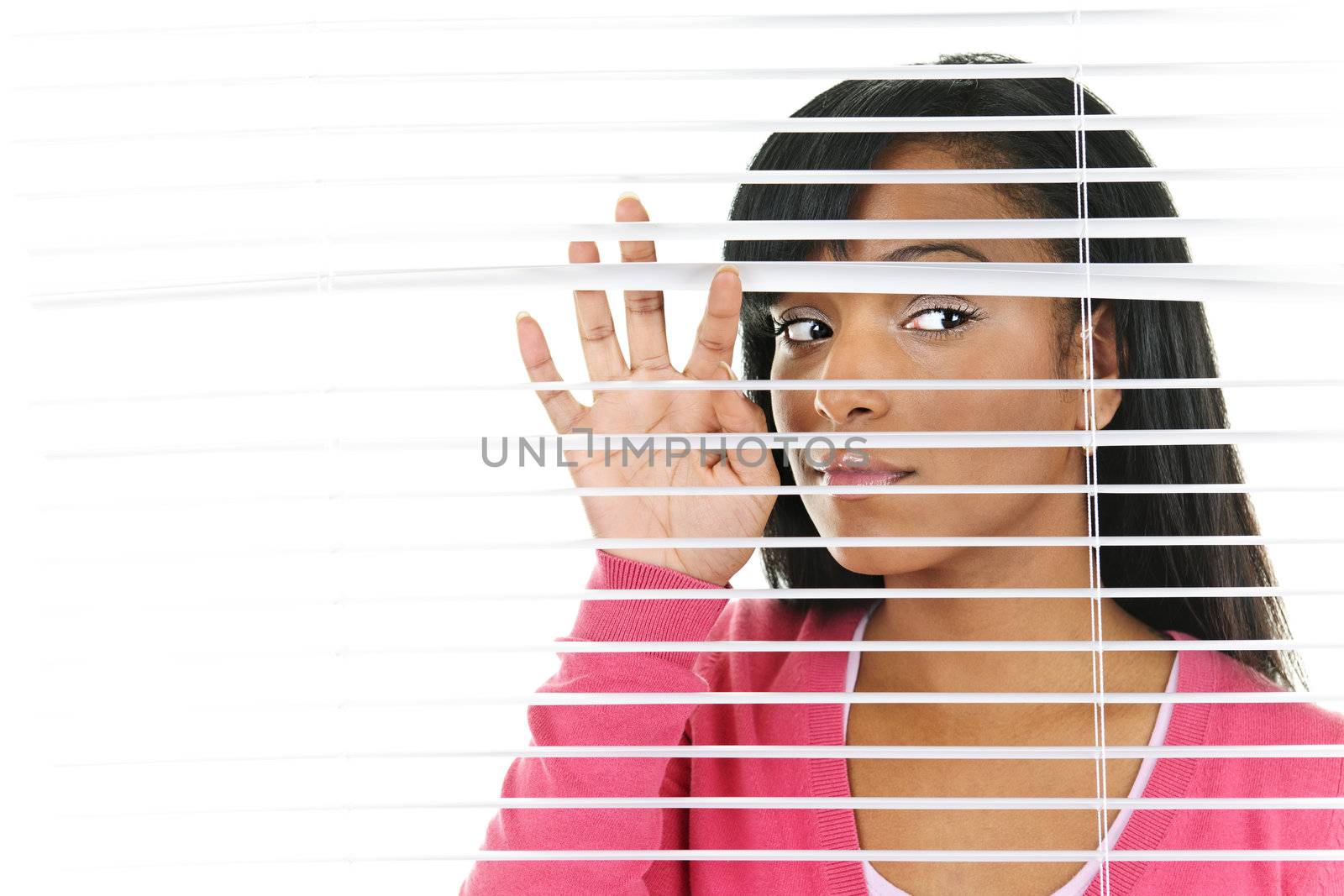 Young black woman looking through horizontal venetian blinds