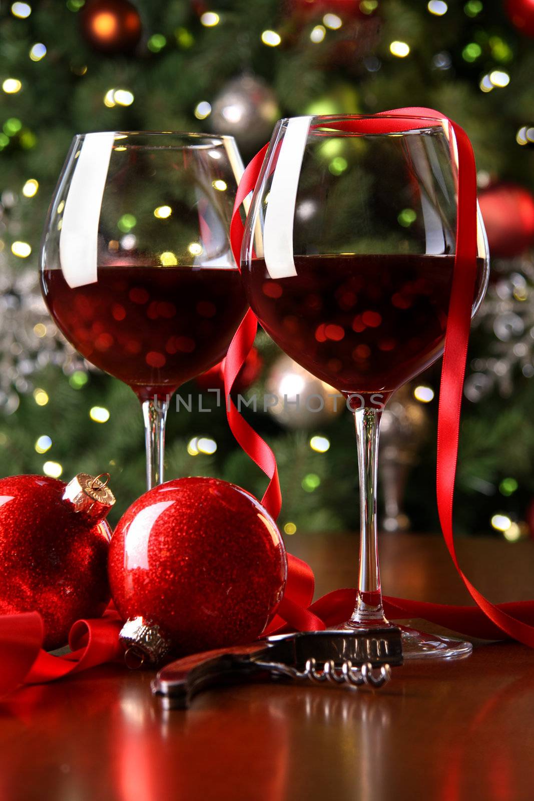 Holiday background with glasses of red wine while trimming tree
