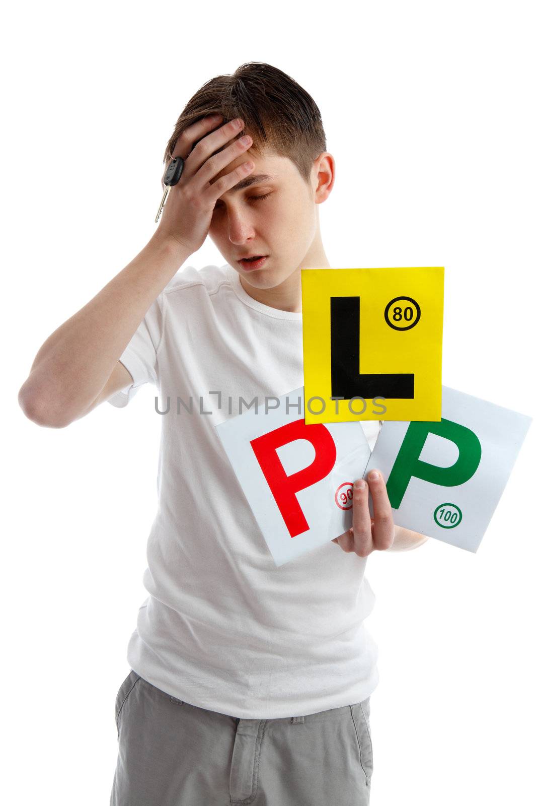 Teenage boy holding L and P plate driving licence signs for car and looking forlorn.  He may need to take more expert driving tuition to avoid another fail in driving examination.