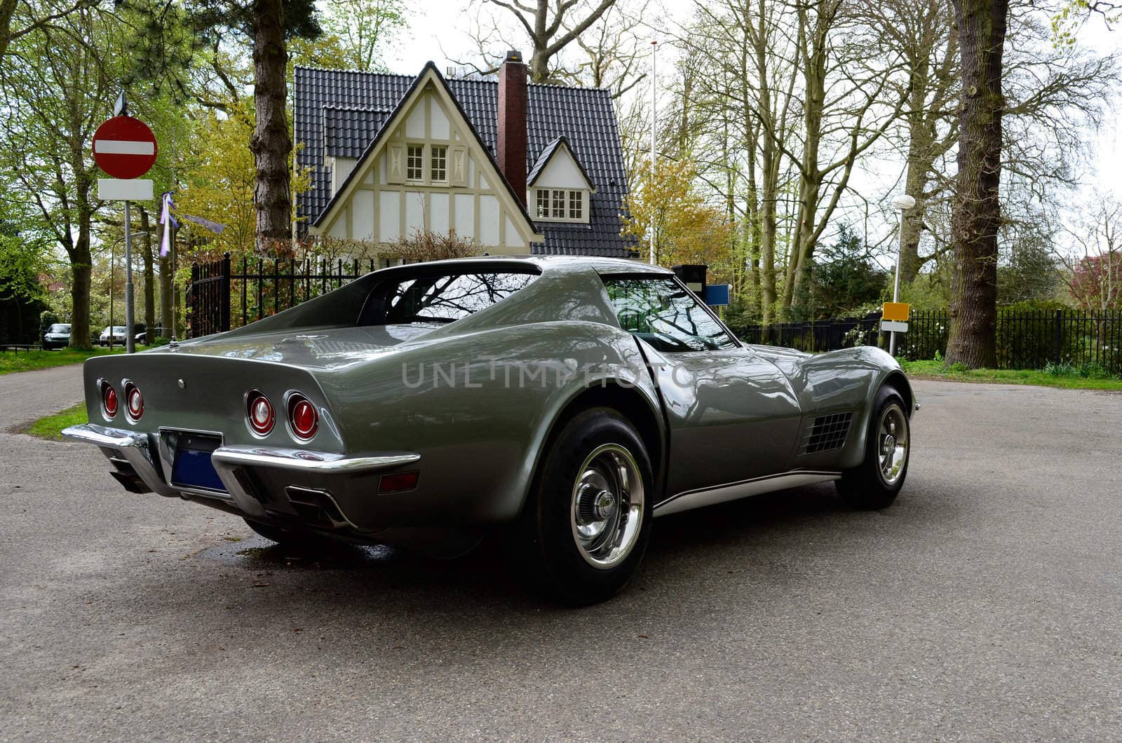 Iconic sportscar Chevrolet Corvette C3 Stingray in silver-grey in front of a luxury house.