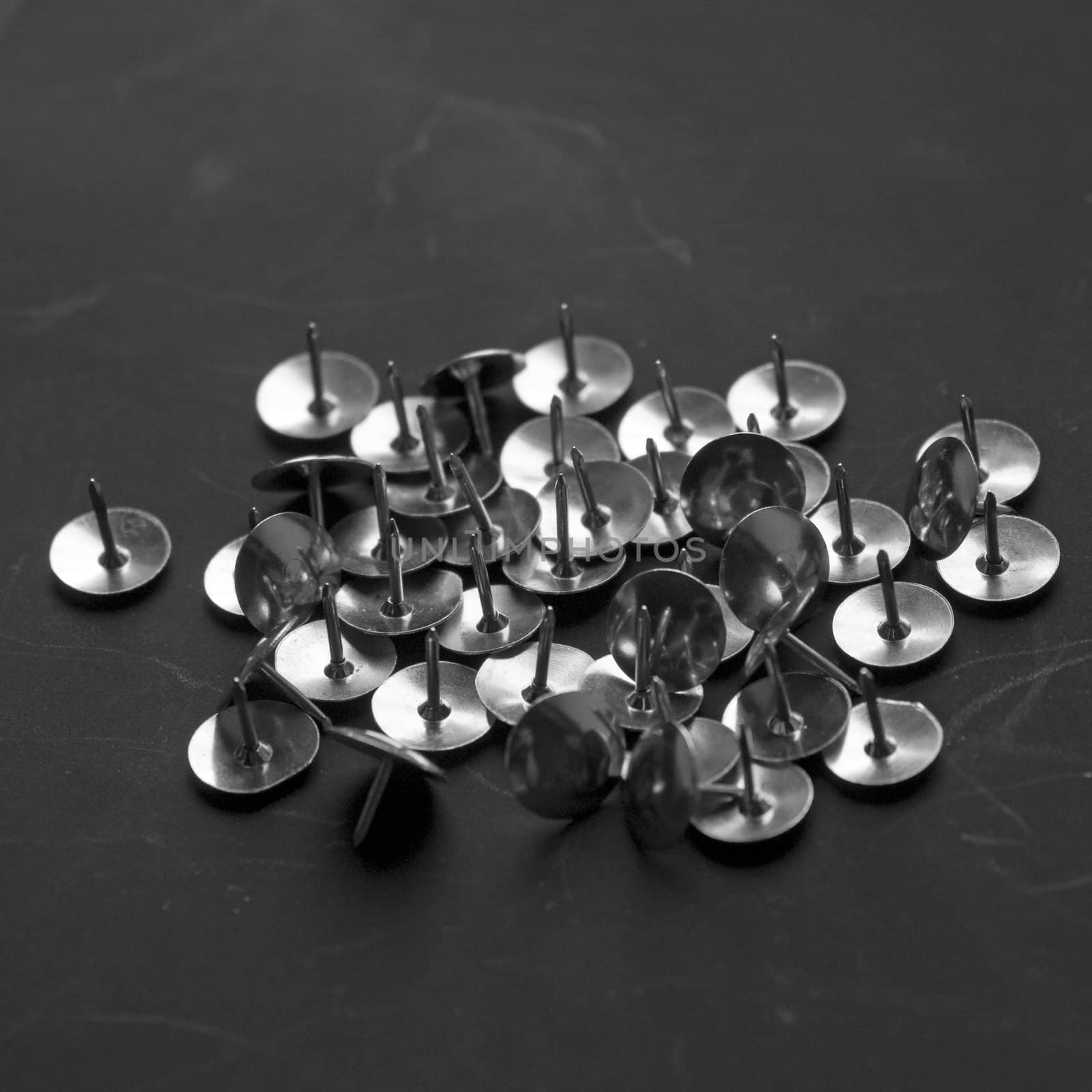 Heap of metal pushpins on a black background