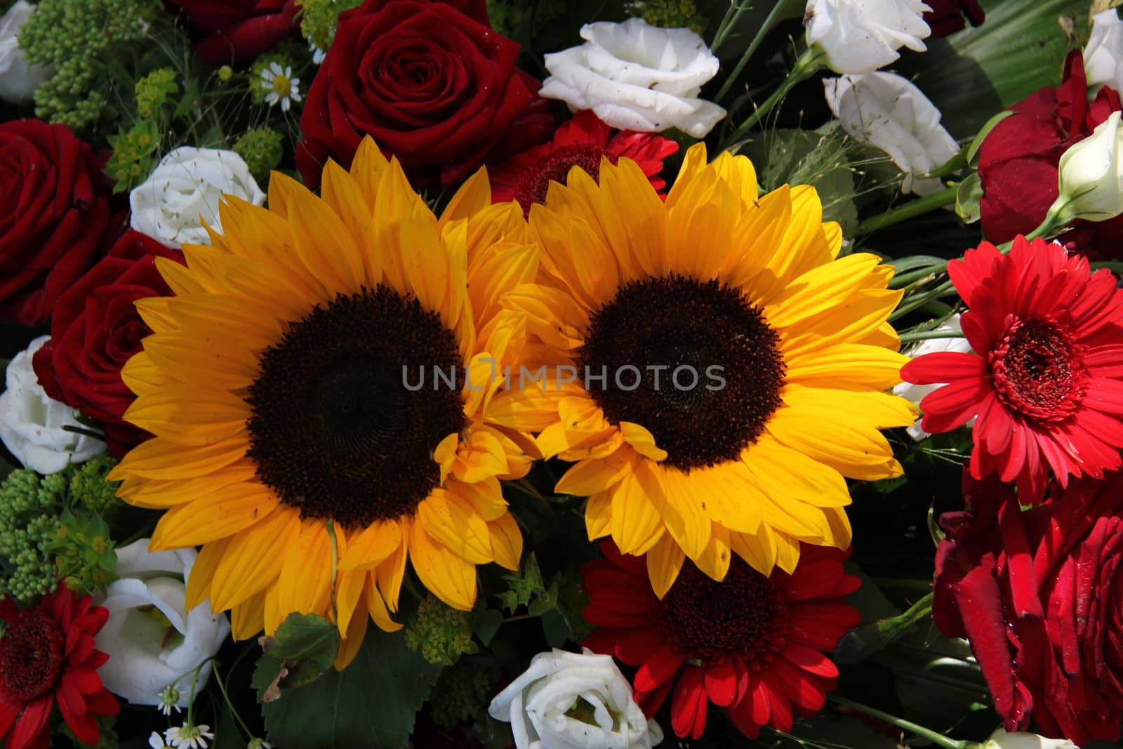 Bright yellow sunflowers and big red roses in a floral arrangement