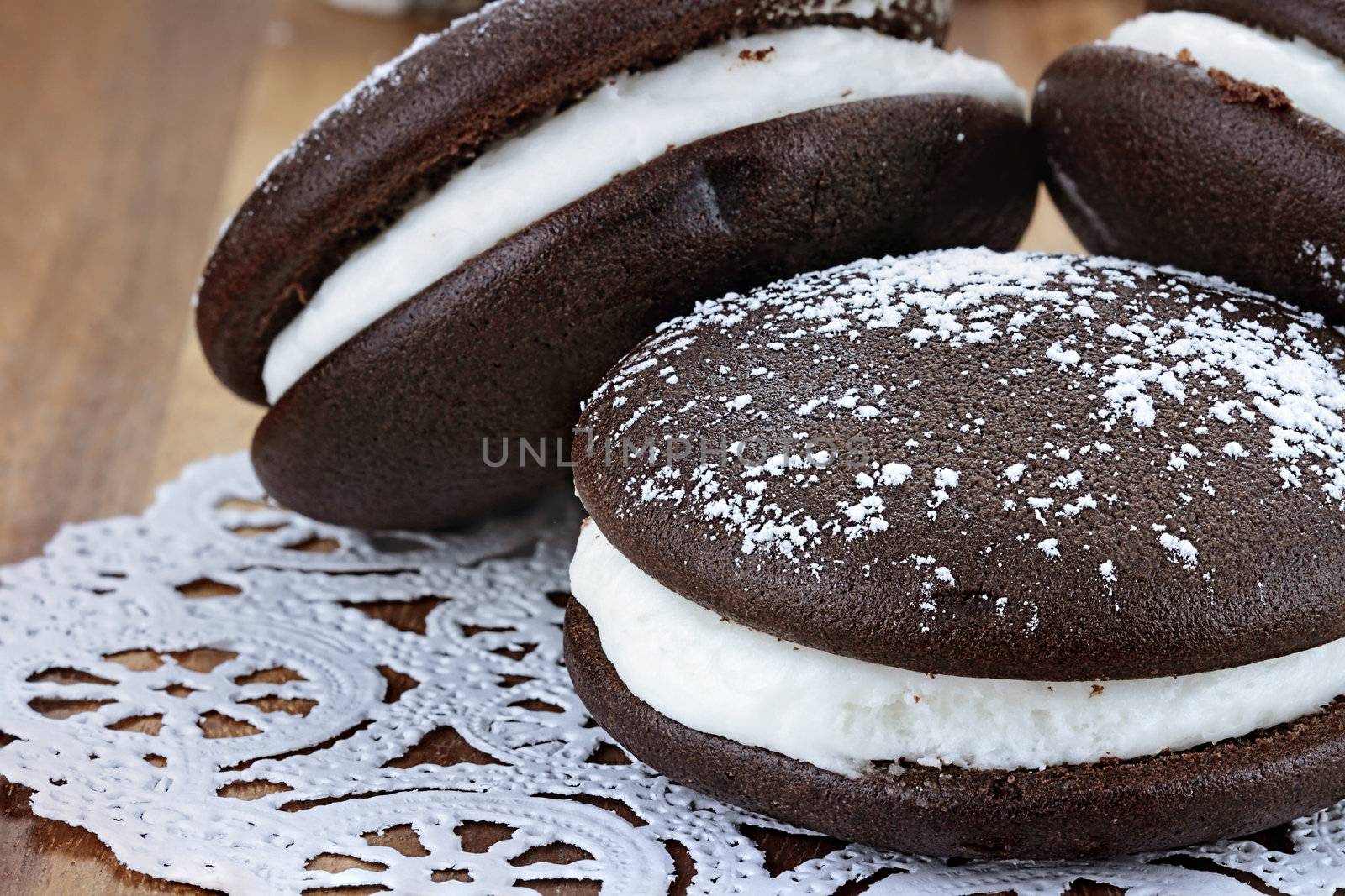 Macro image of three whoopie pies or moon pies with powdered sugar. Shallow depth of field.