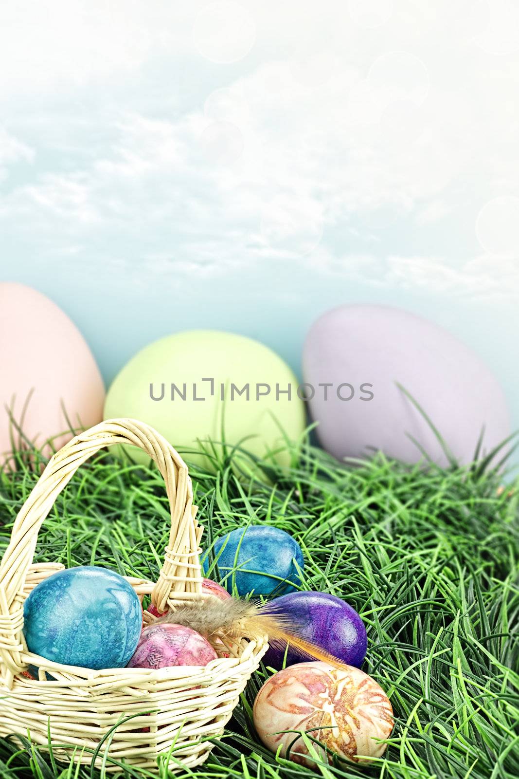 Basket full of hand painted tie dyed Easter eggs in the grass. Extreme shallow DOF.
