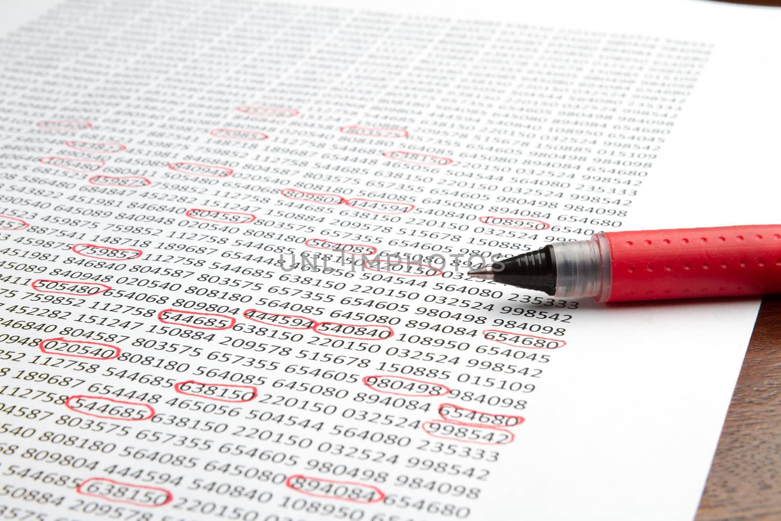 Red pen sitting on a piece of paper with numbers circled. Paper looks as though it is a report with important numbers
