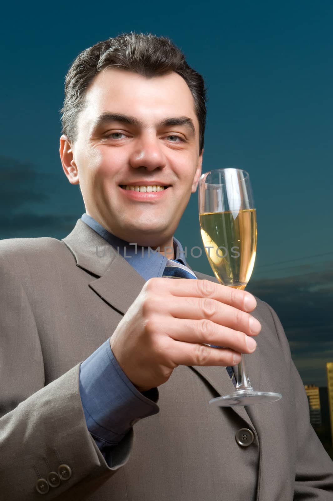 man in a suit against the evening sky with a glass of champagne