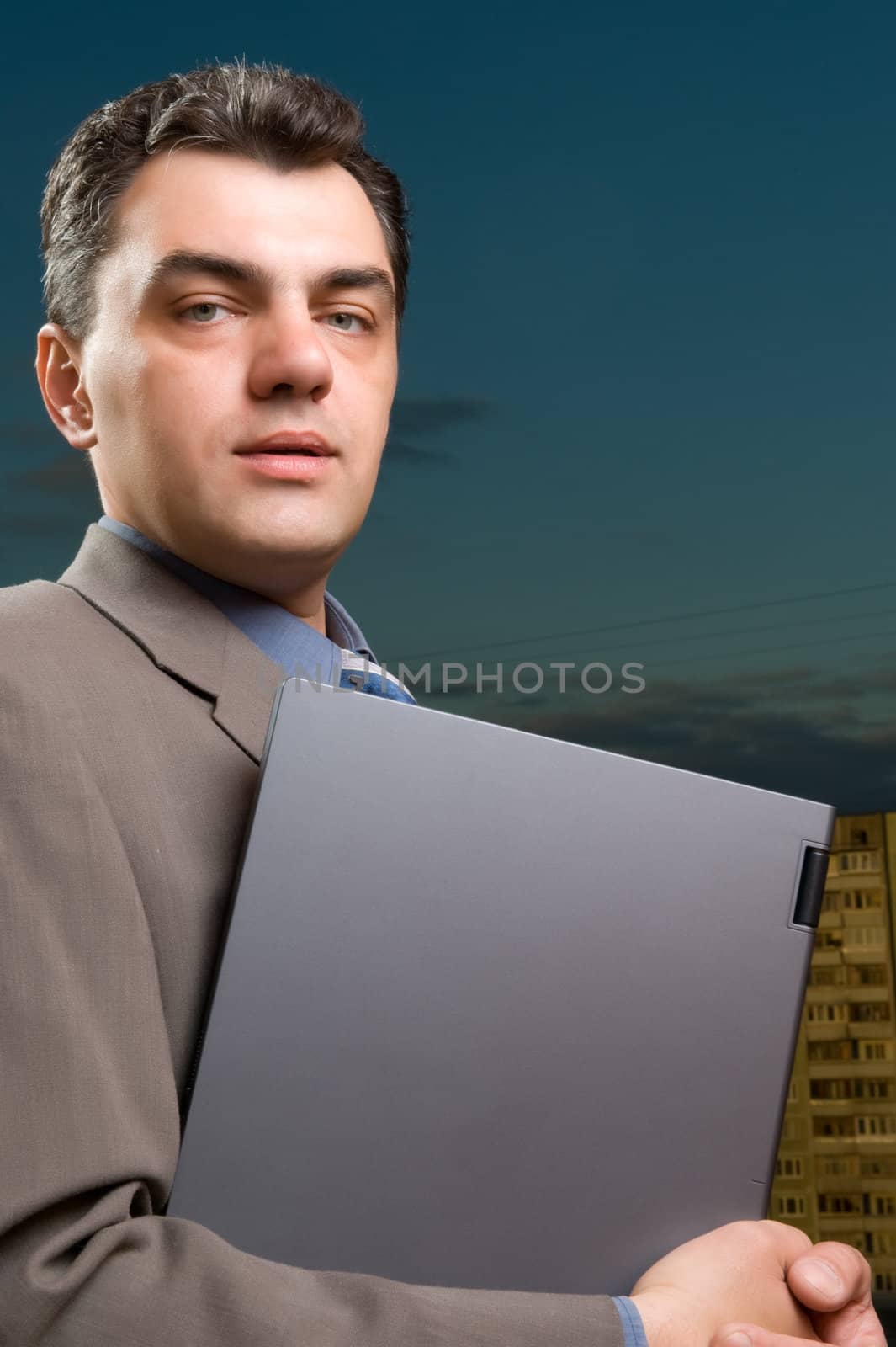 man in a suit against the evening sky with laptop