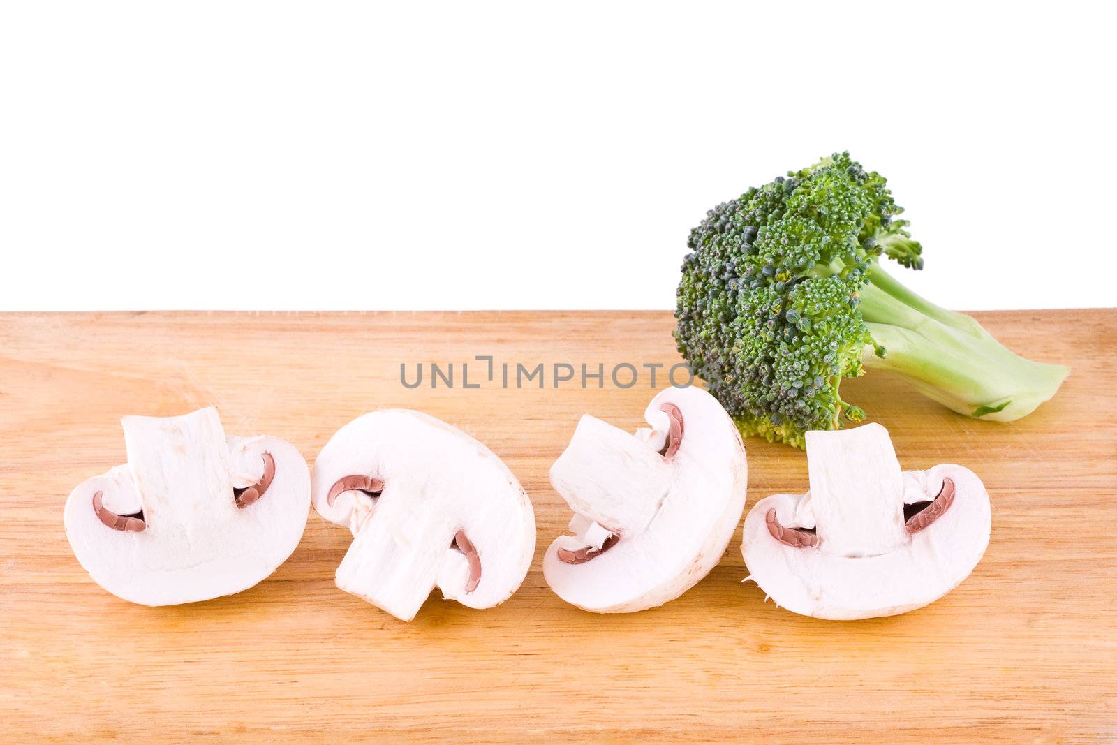 Fresh mushrooms and broccoli on the wooden cutting board