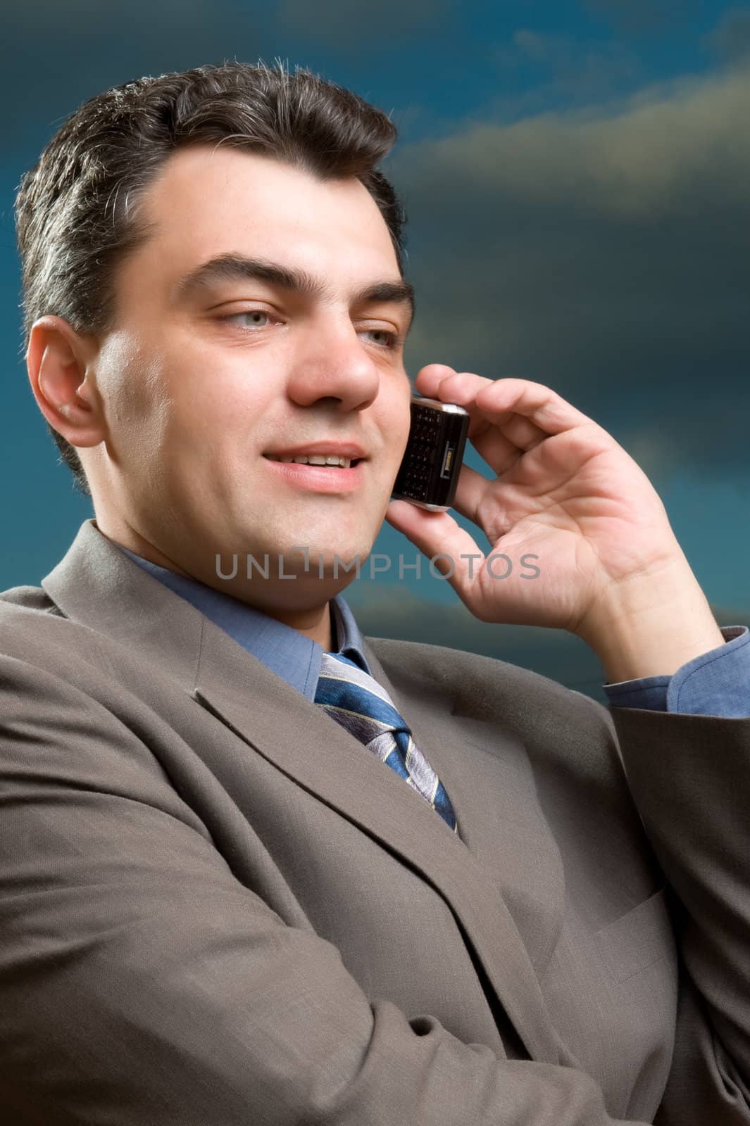 man in a suit against the evening sky with mobile phone