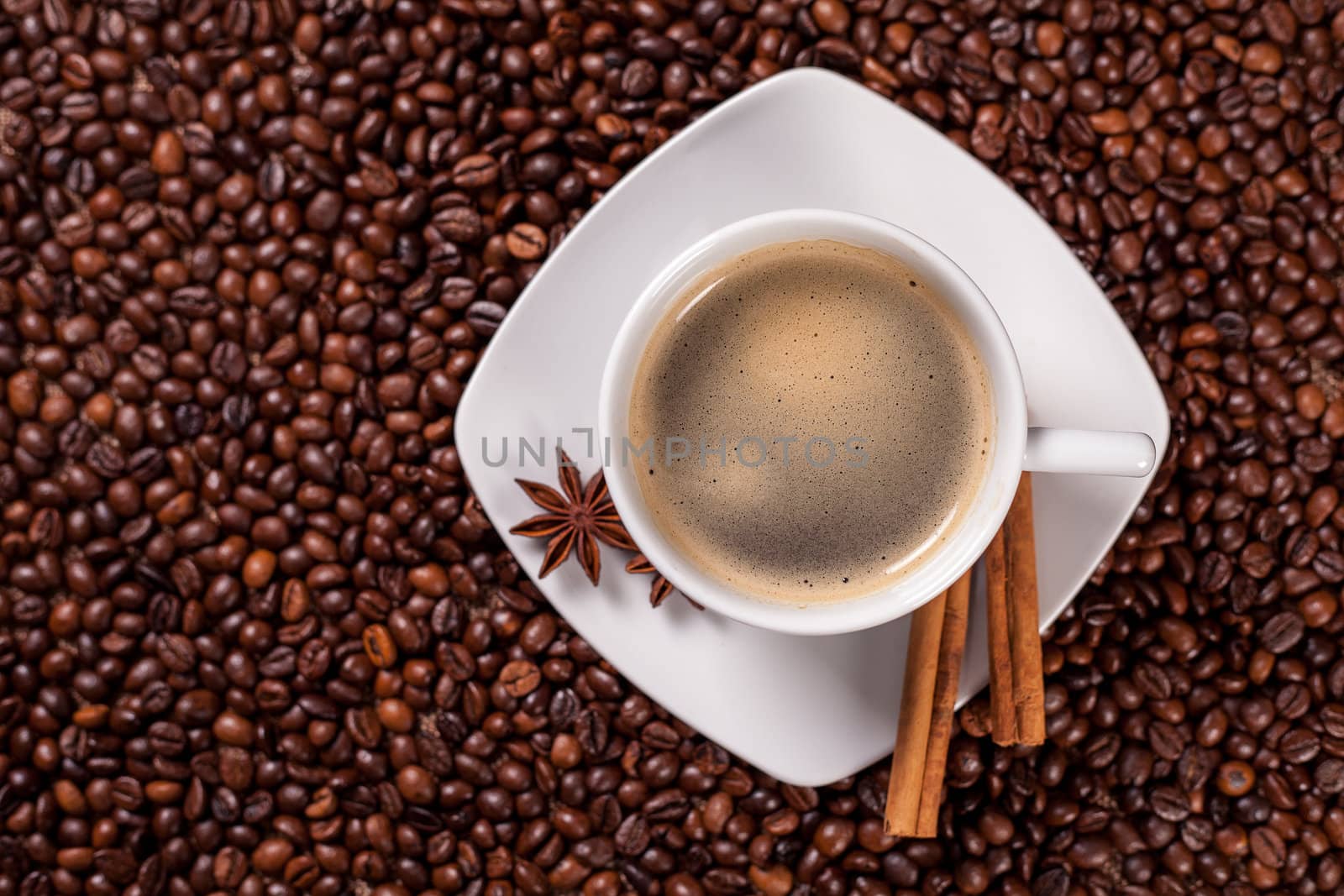 High angle view of a coffee cup with cinnamon on coffee beans background 