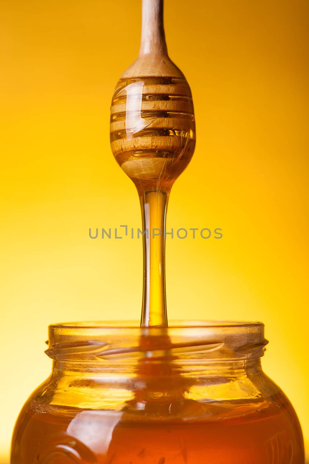 Flowing golden honey over yellow background 