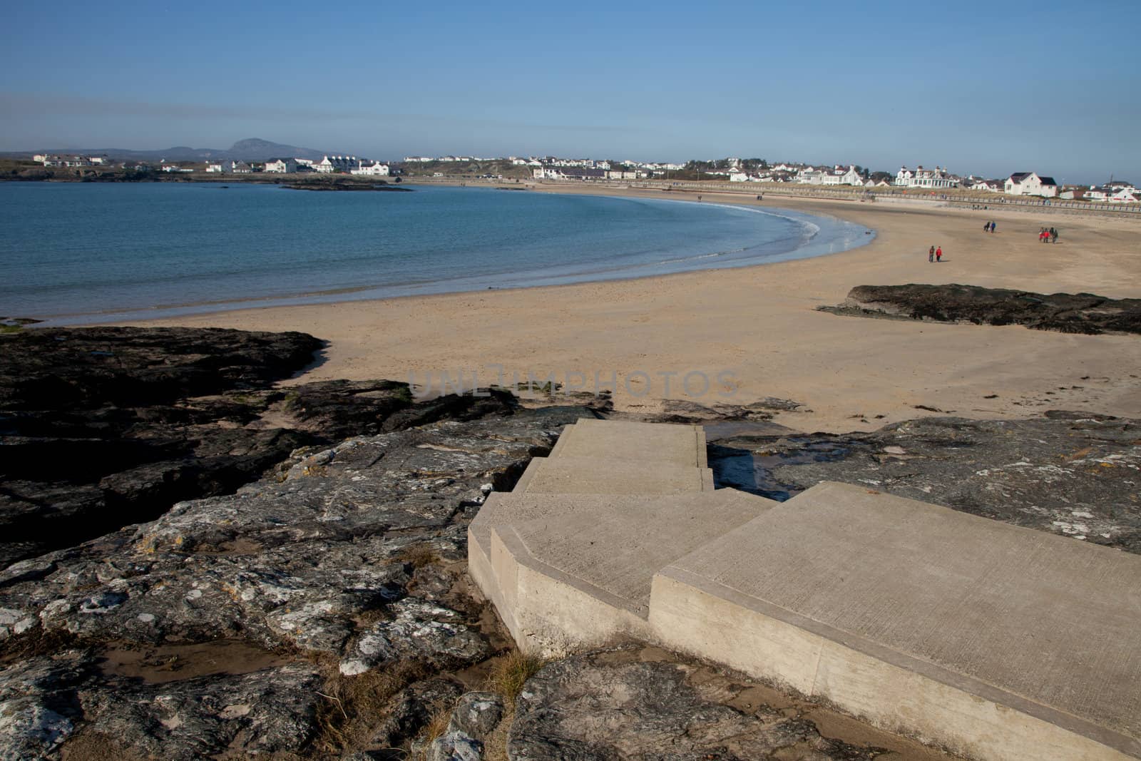 Concrete set of steps Trearddur bay beach, Anglesey, Wales, UK, with people in the distance.