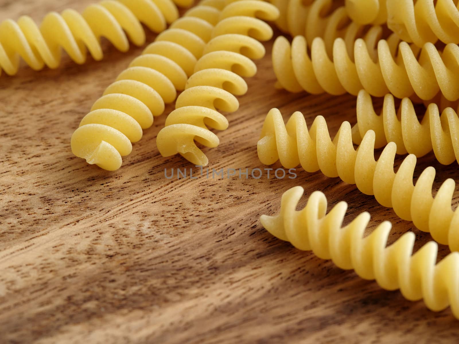 Closeup photo of fusilli dry pasta on a wood table.
