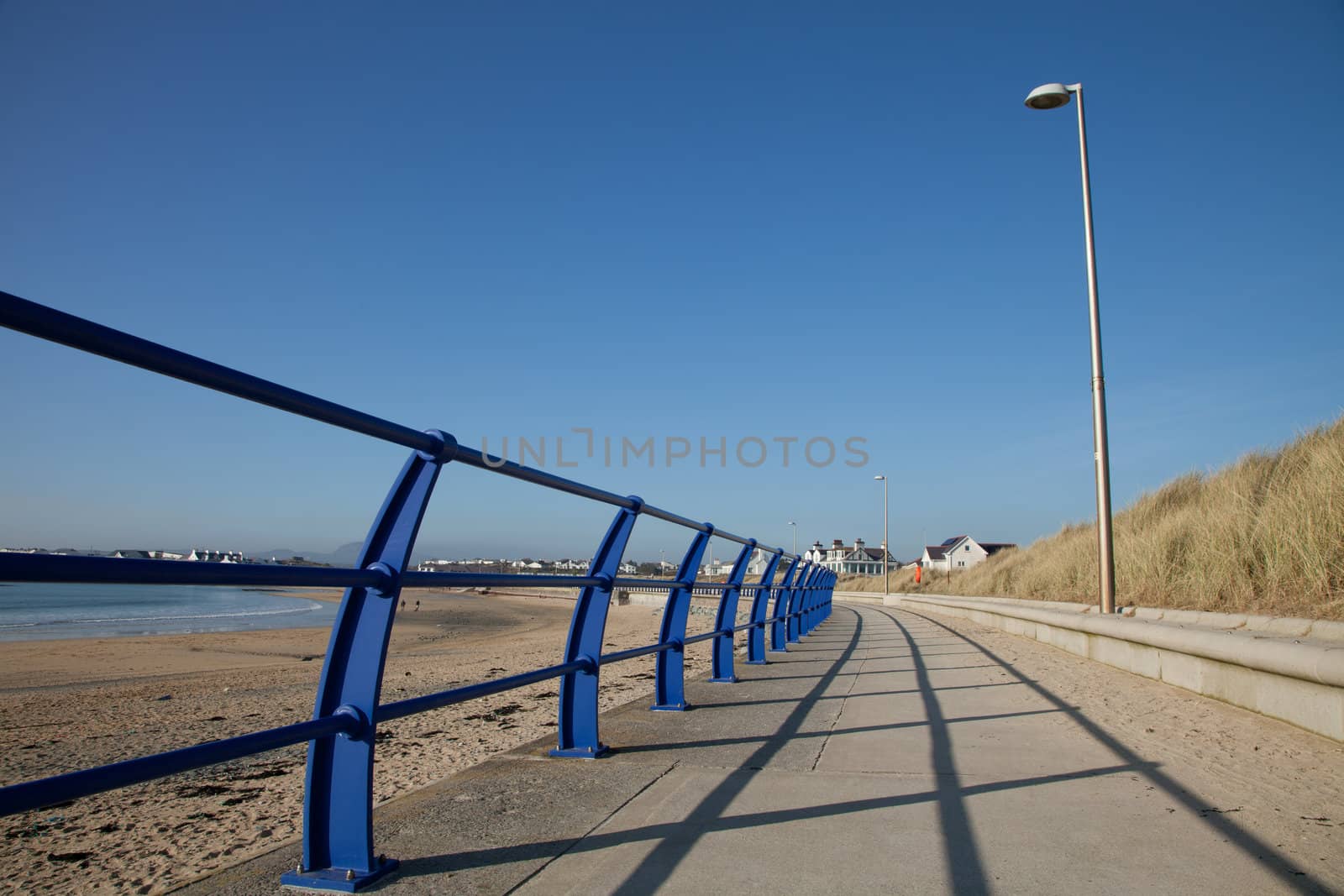 Footpath and railings with a lampost skirting the edge of a beach, Trearddur bay, Anglesey, Wales, UK.