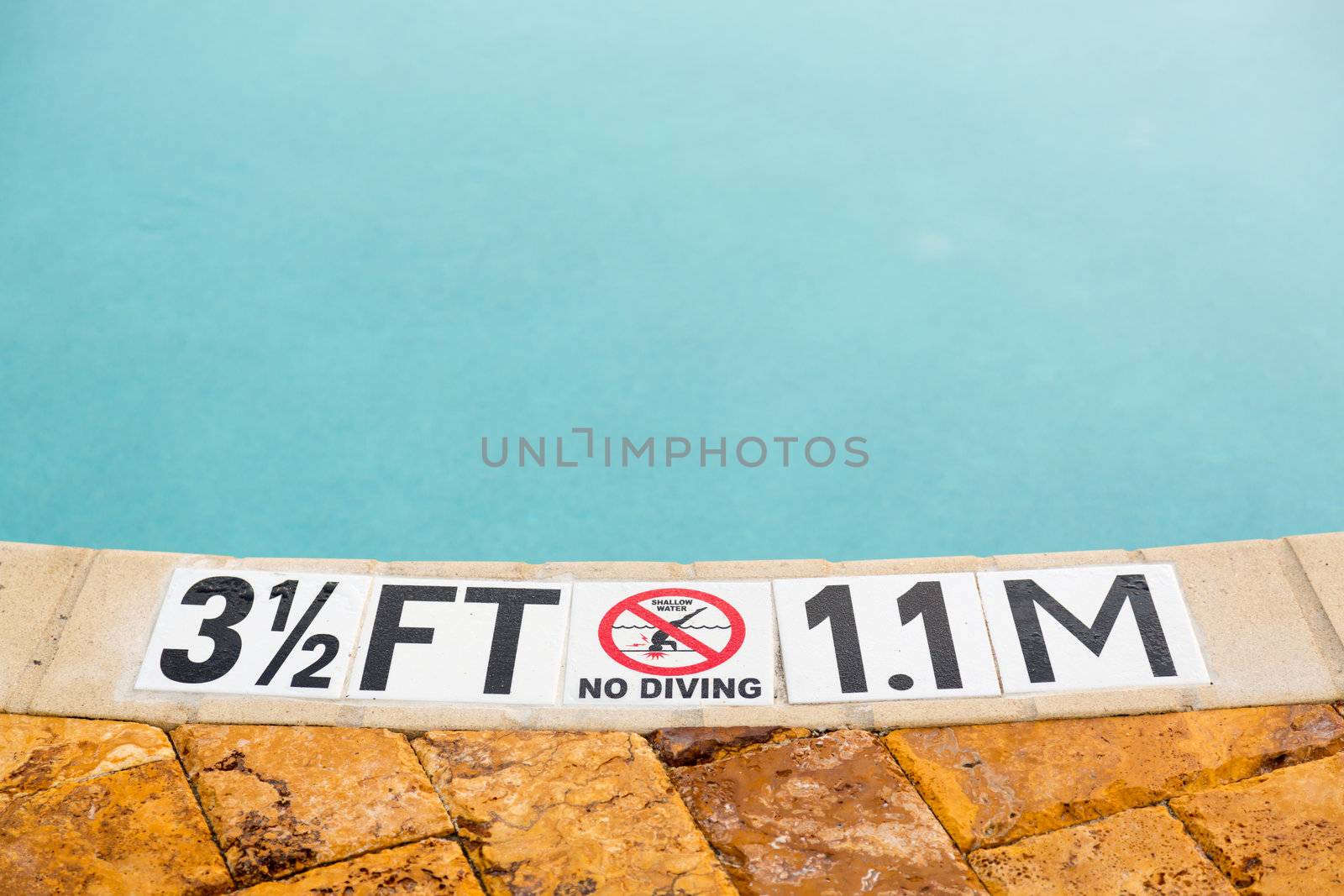 Sign showing 3.5 ft depth on edge of blue swimming pool with no diving