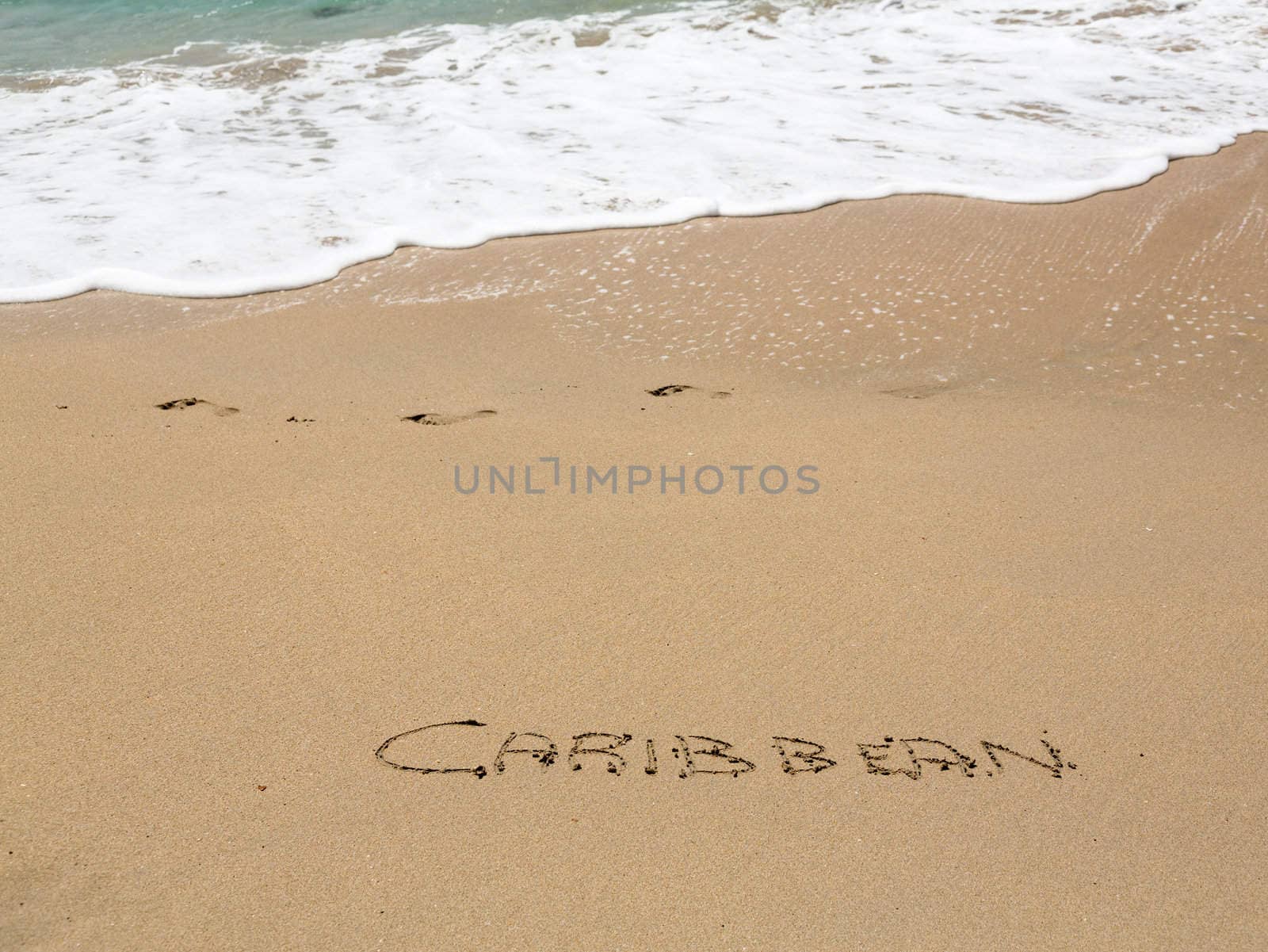 Caribbean words written into sand on beach by sea in St Thomas