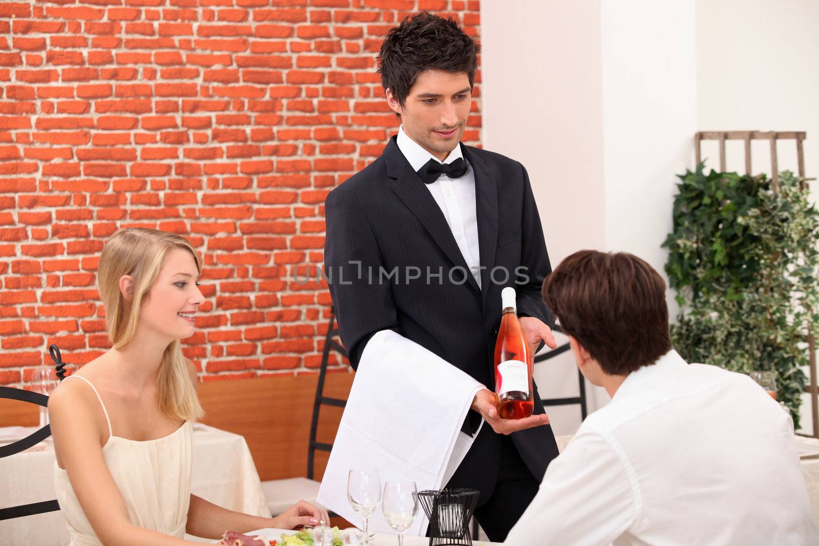 Young couple choosing rose wine in a restaurant by phovoir