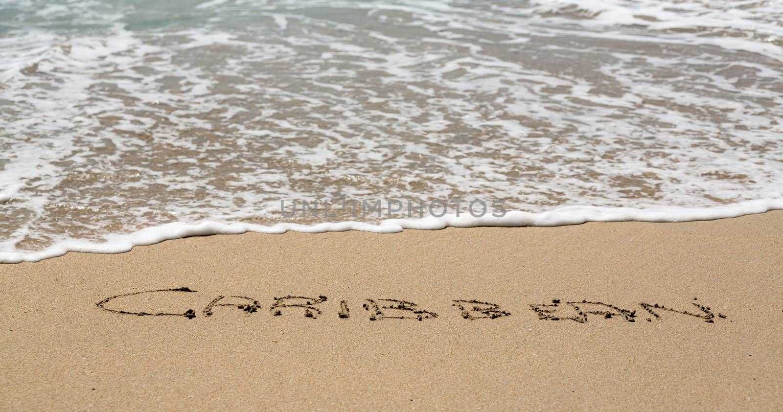 Caribbean words written into sand on beach by sea in St Thomas