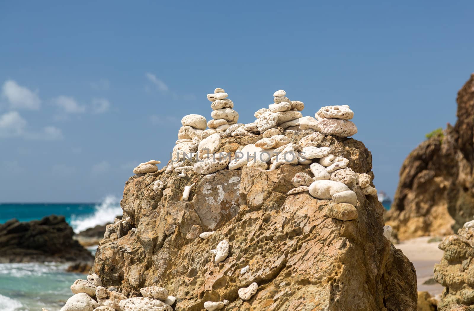Multiple stacks of pebbles on rock by sea shore with sun lighting the piles
