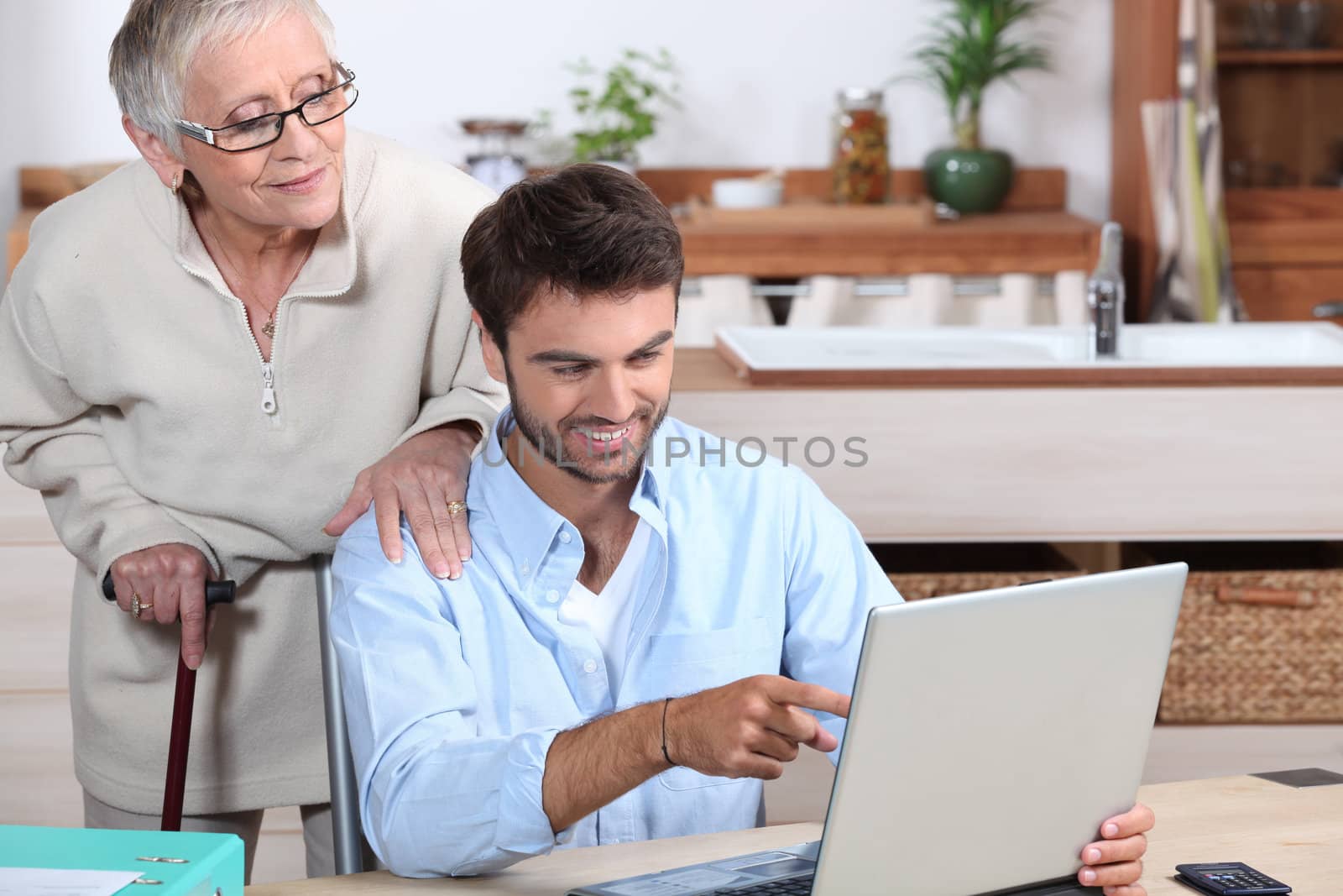 Man showing old lady how to use computer by phovoir