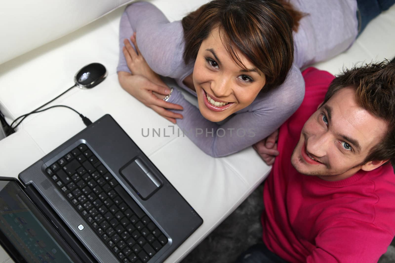 couple having fun at home with their laptop by phovoir