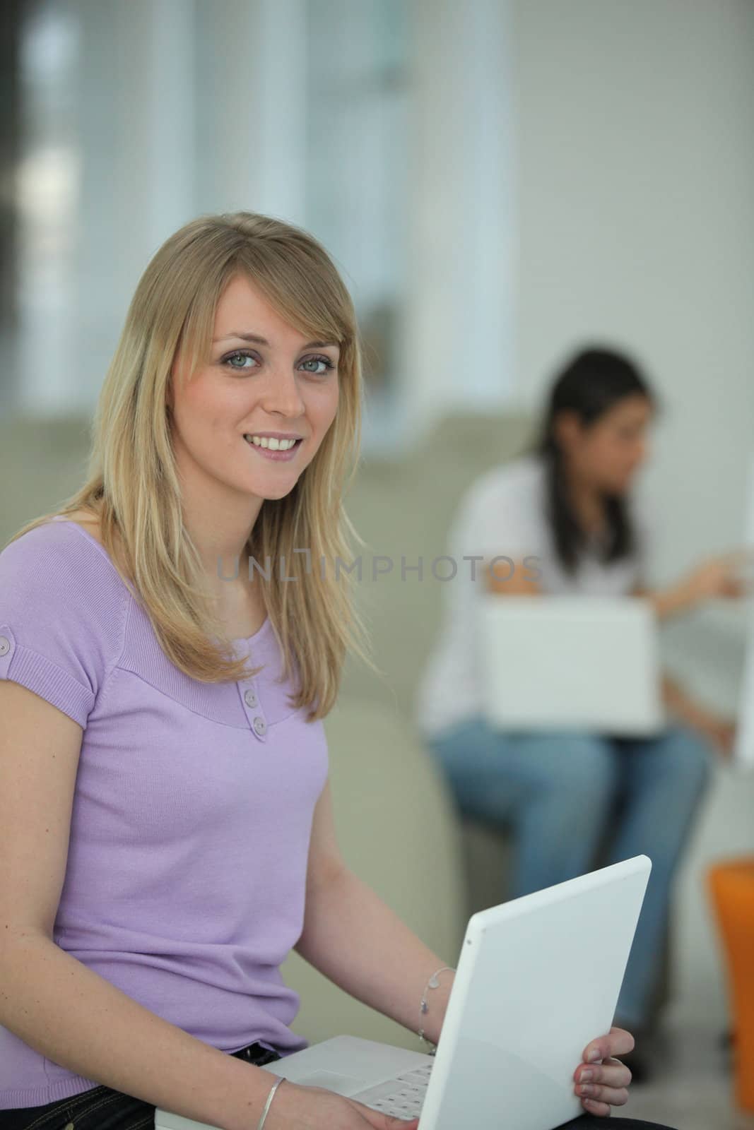 Young woman sitting with a laptop on her lap by phovoir