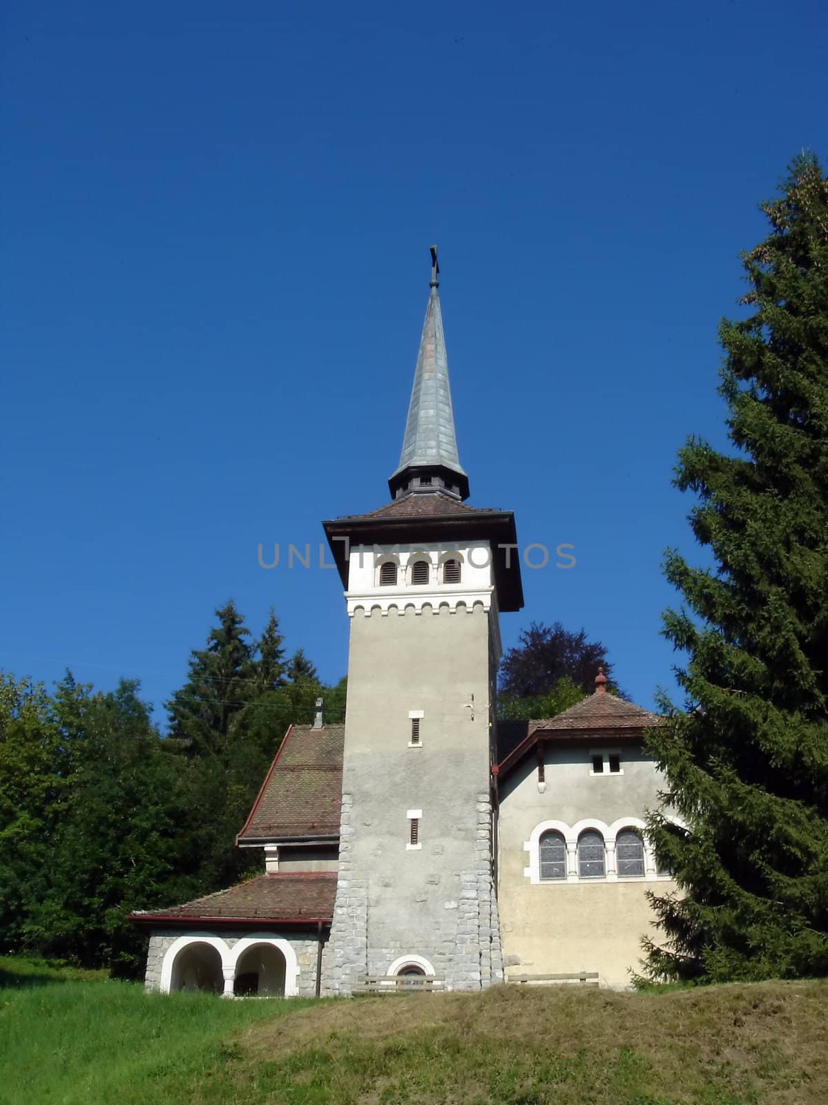 Facade and belltower of a small church surrounded by trees and nature by beautiful weather