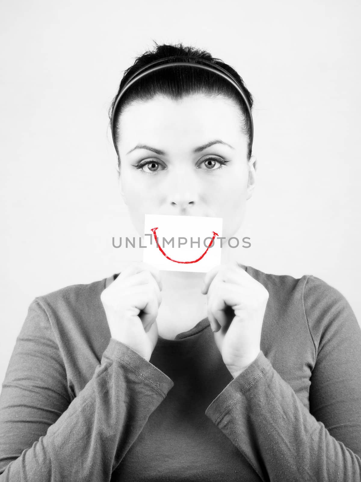 Black and white portrait of beautiful sad woman with fake smile on white background.