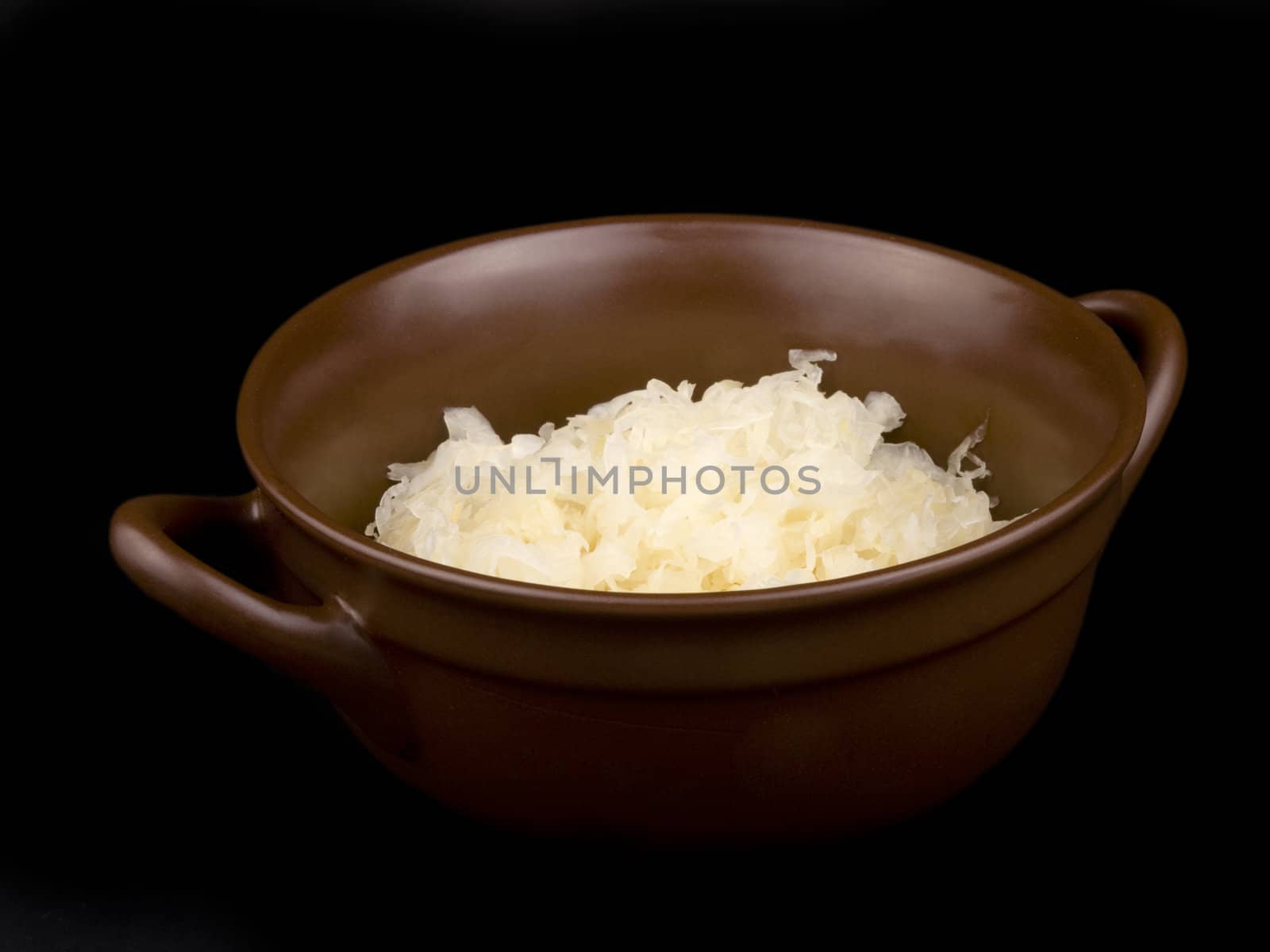 Ceramic bowl filled with sour cabbage on black background