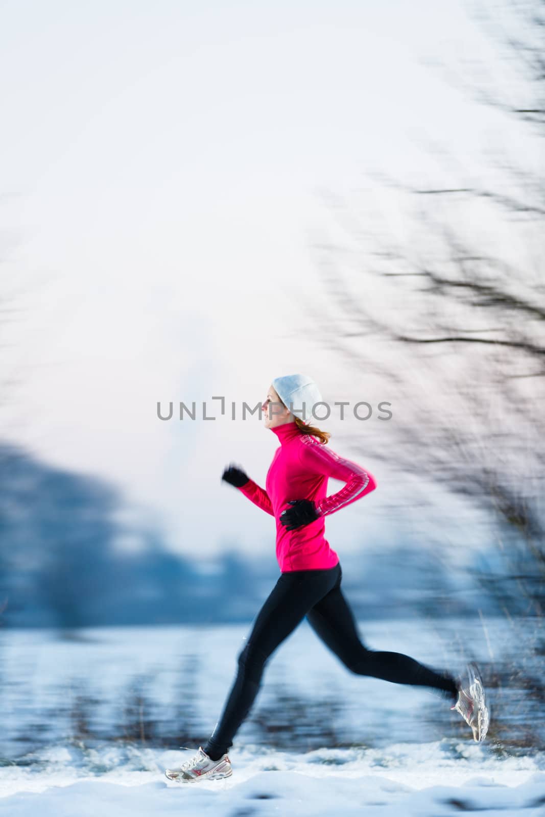 Young woman running outdoors on a cold winter day (motion blurred image)