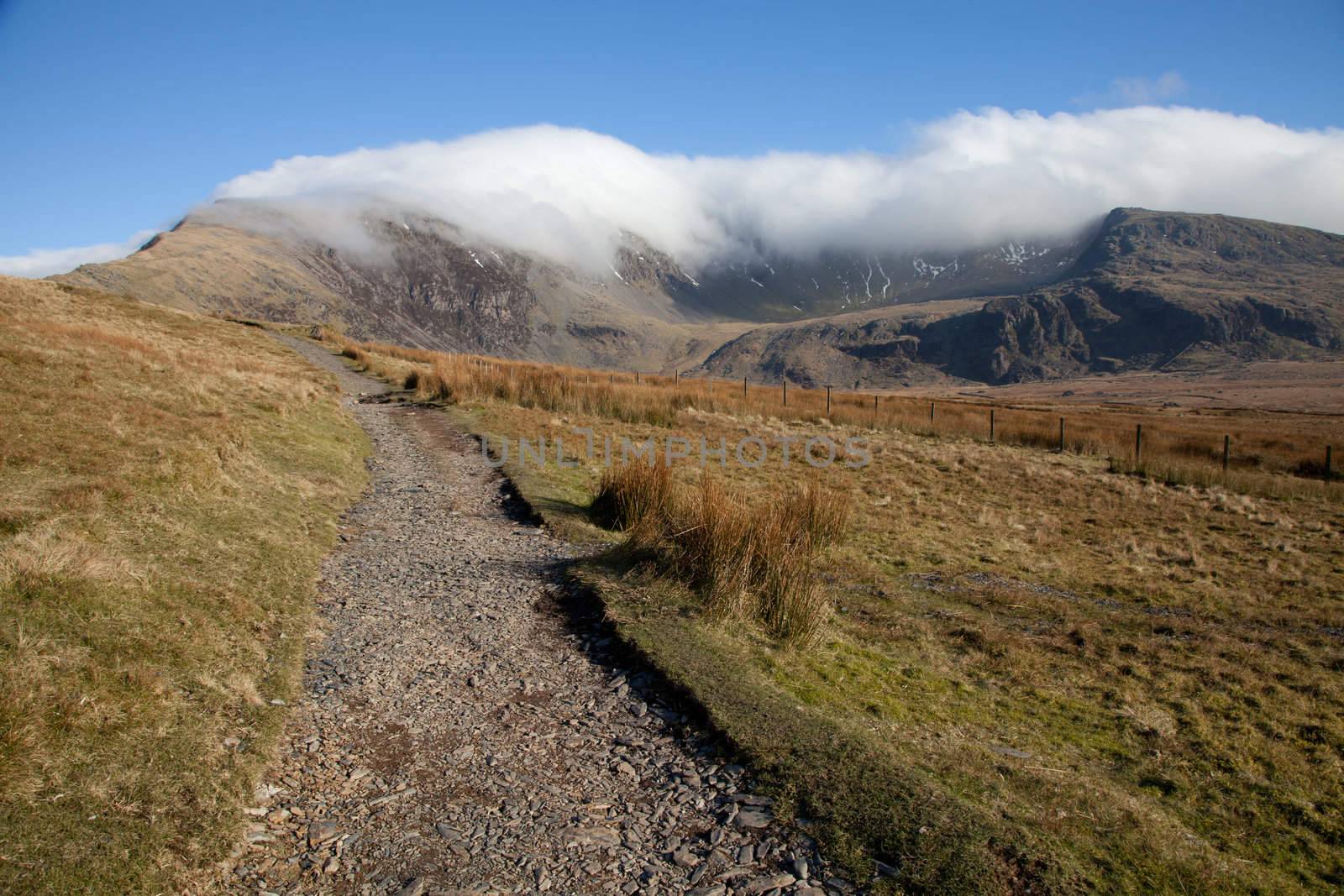 The Snowdon Ranger path cuts through moorland towards mount Snowdon. A cloud inversion is developing over the peak in the distance.