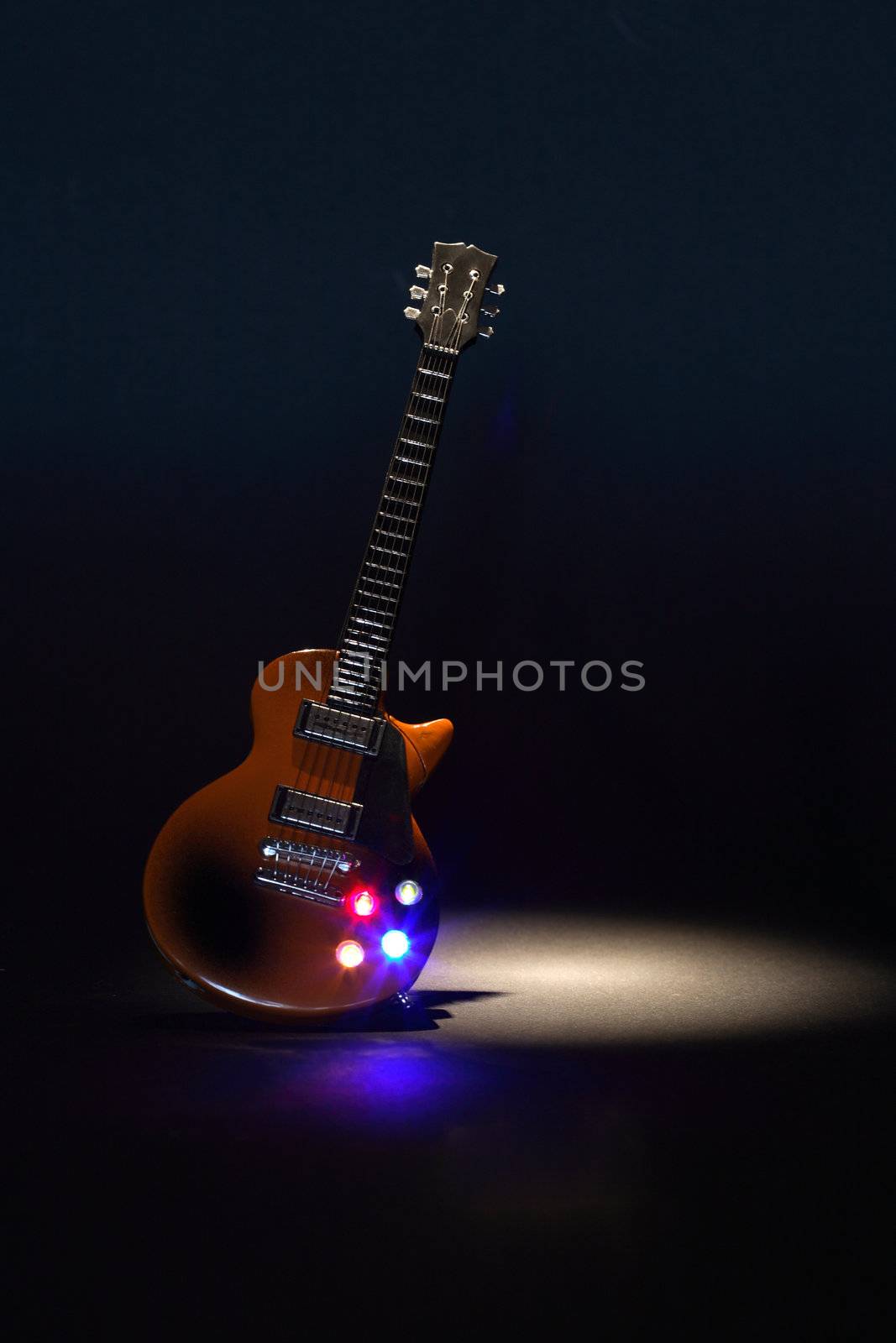 Electric guitar under beam of light on dark background