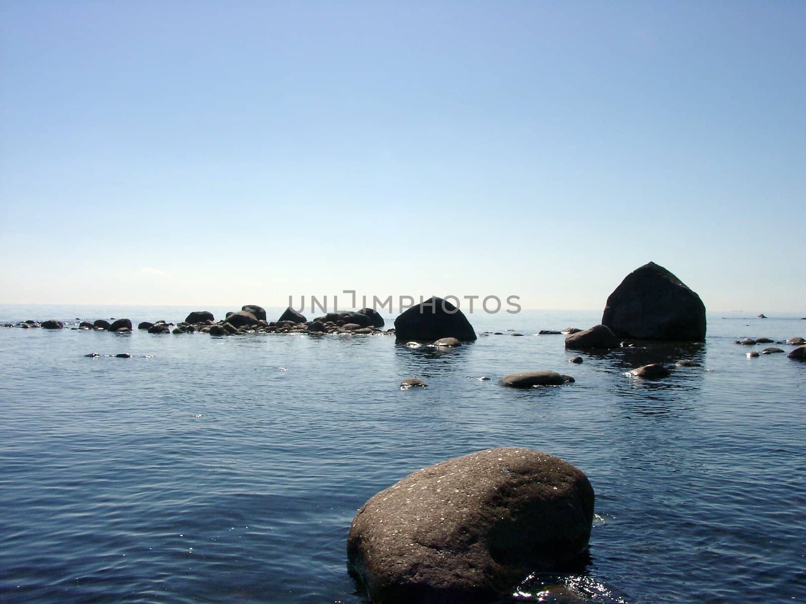 Early morning view of stones and horizon at Finnish Gulf by summer.