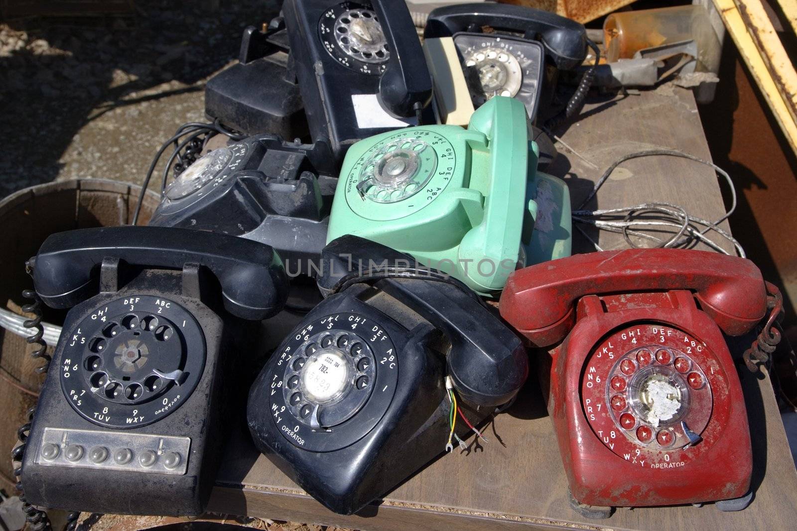 Stack of old broken rotary telephones on table.