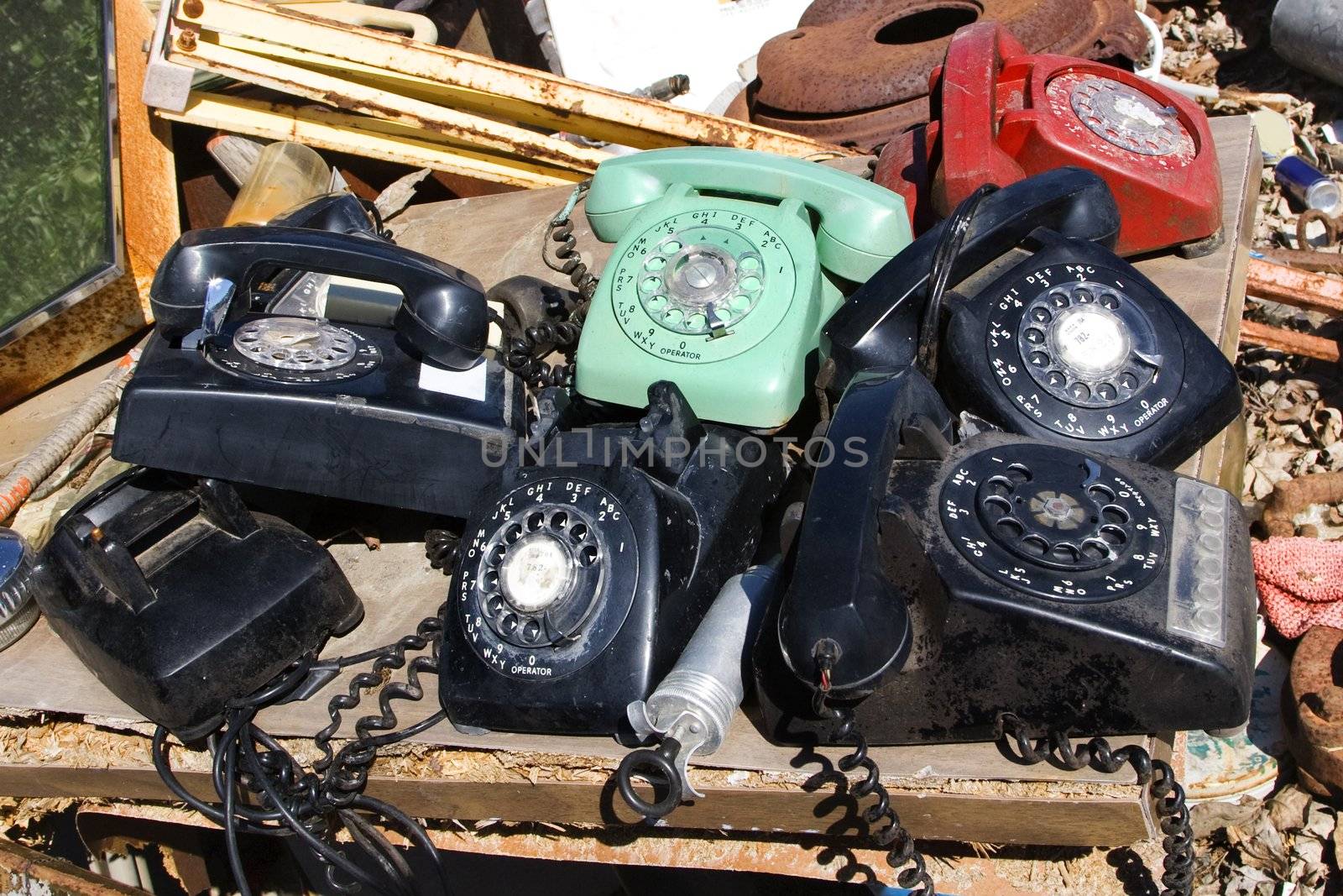 Stack of old broken rotary telephones on table.