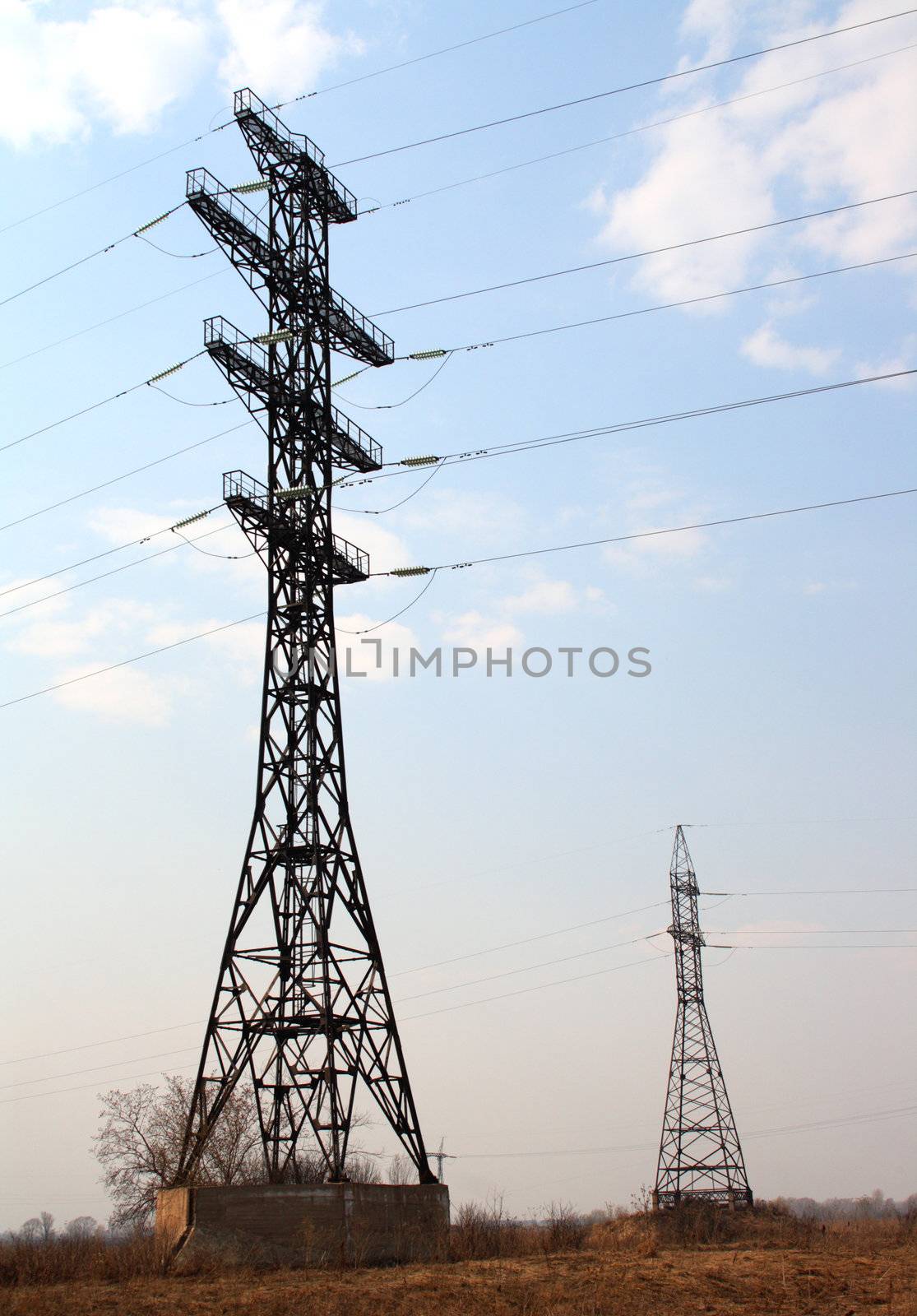 two tall electric masts in field under blue sky