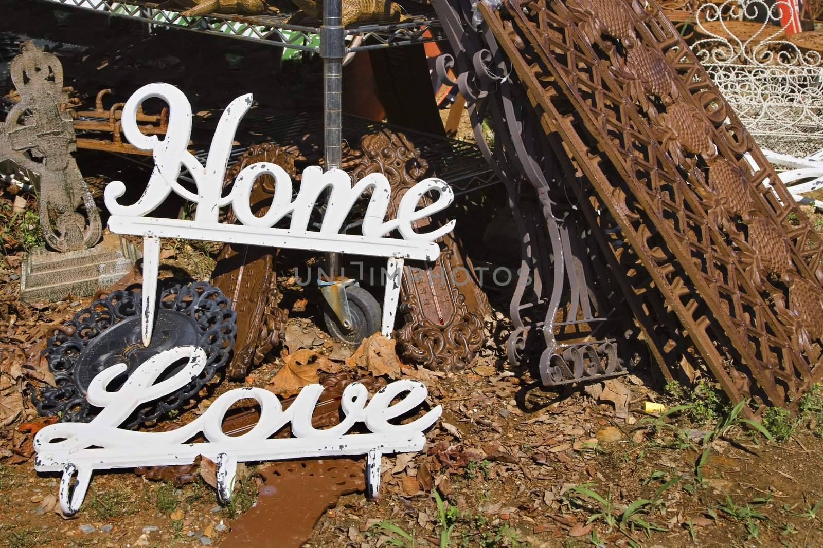 Metal garden decorations of words Love and Home next to rusted metal objects.