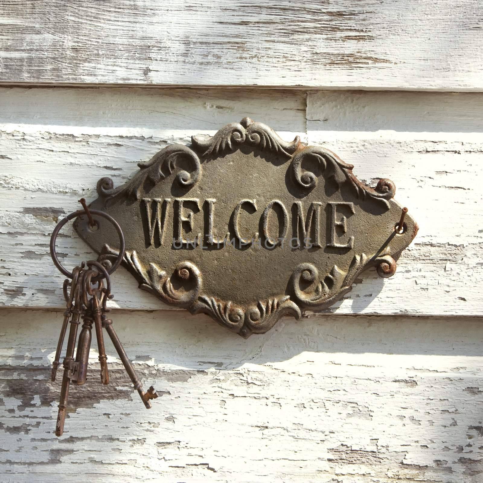 Welcome sign and metal keys on old white peeling building.