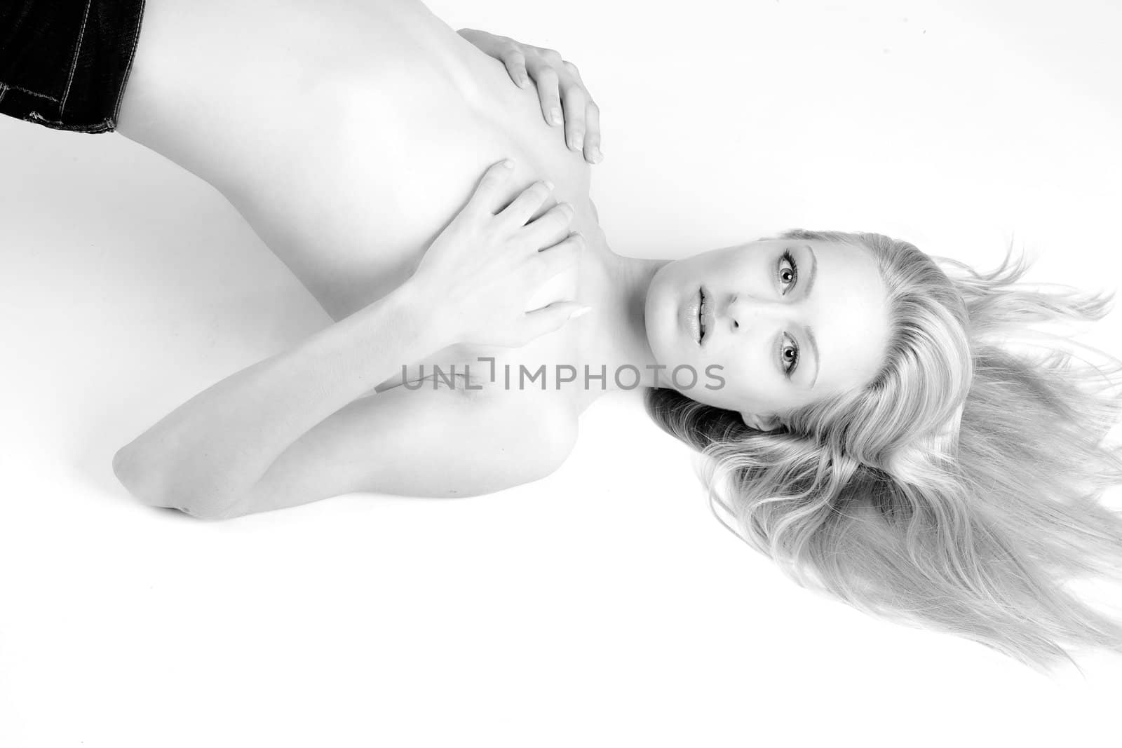 Studio portrait of a blond woman in only jeans lying