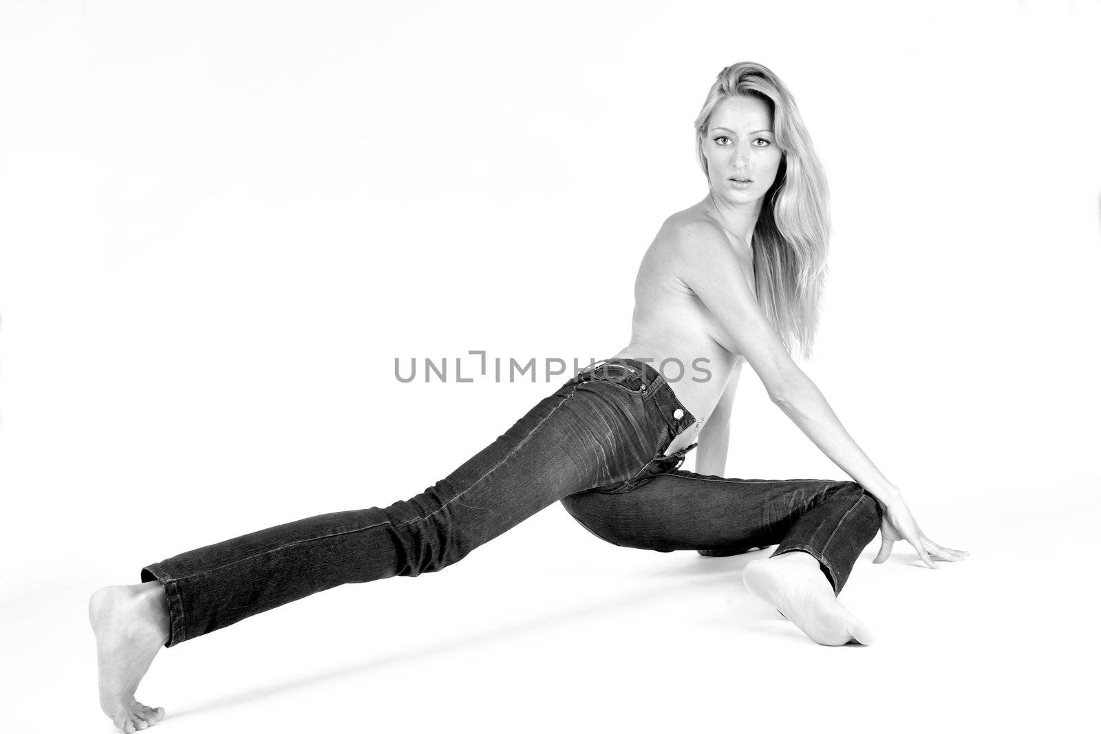 Studio portrait of a blond woman in only jeans in a creative pose