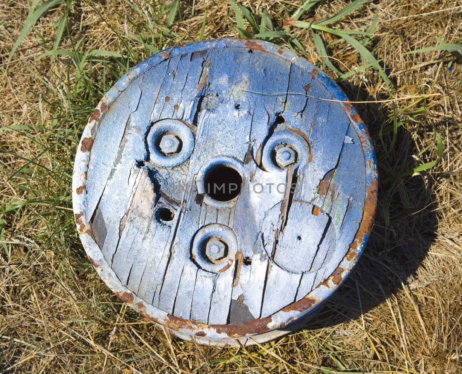 Old round wooden cog lying on ground.