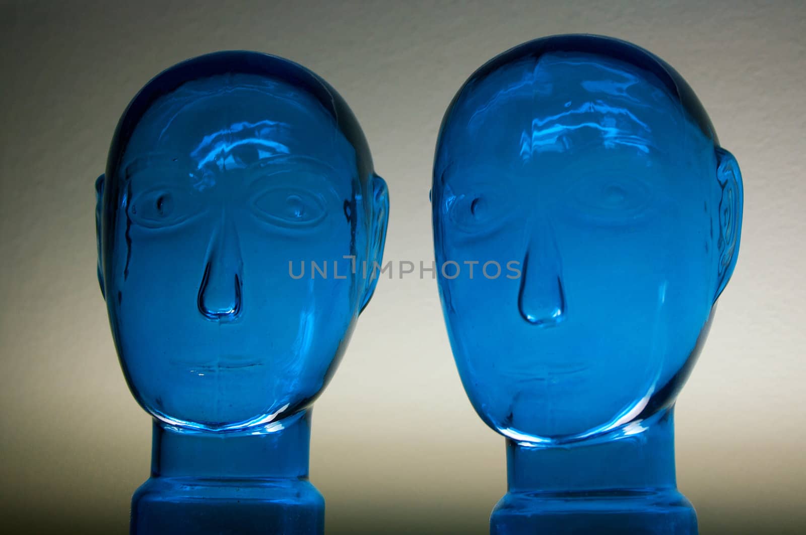 Two glass dark blue heads on a neutral background
