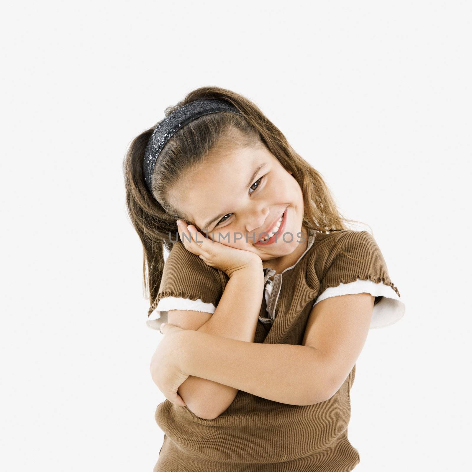 Adorable little hispanic girl standing smiling with cheek in hand.