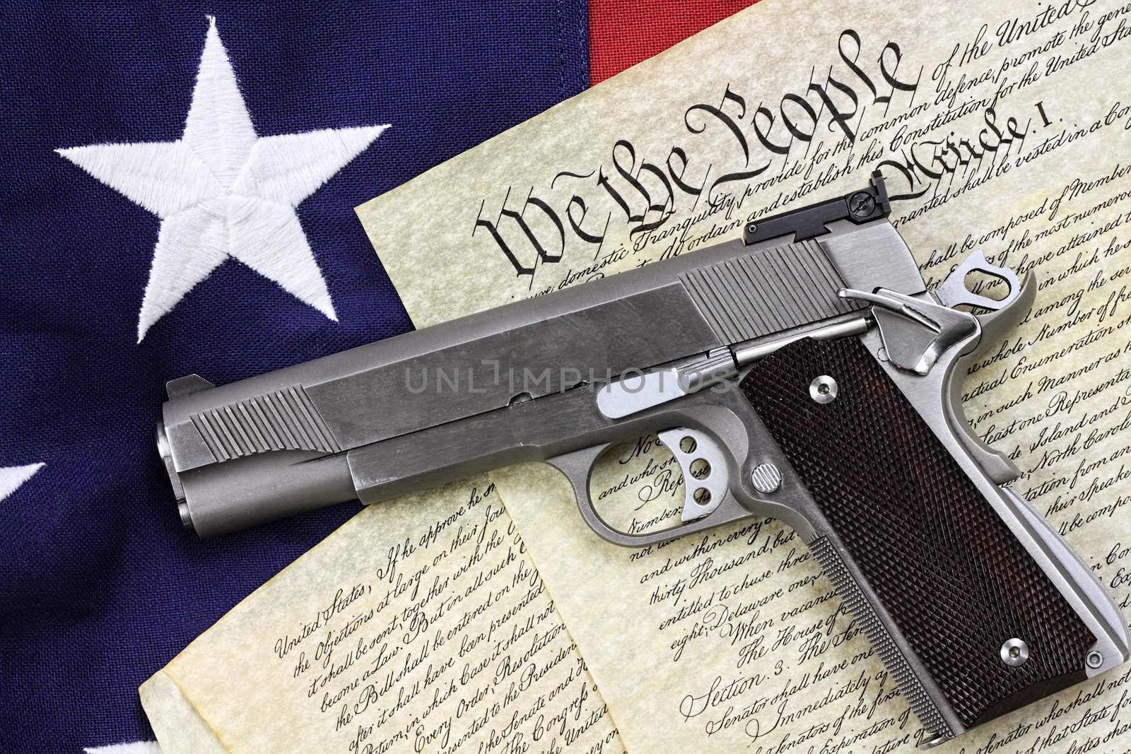 Handgun lying over a copy of the United States constitution and the American flag.

