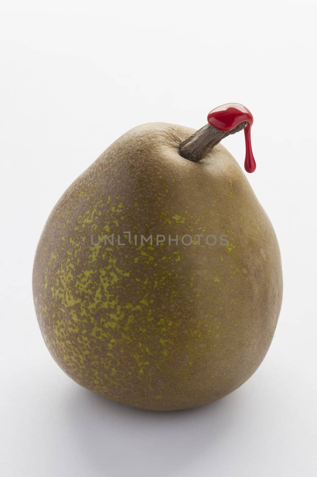 Green pear with red sealing wax on stalk