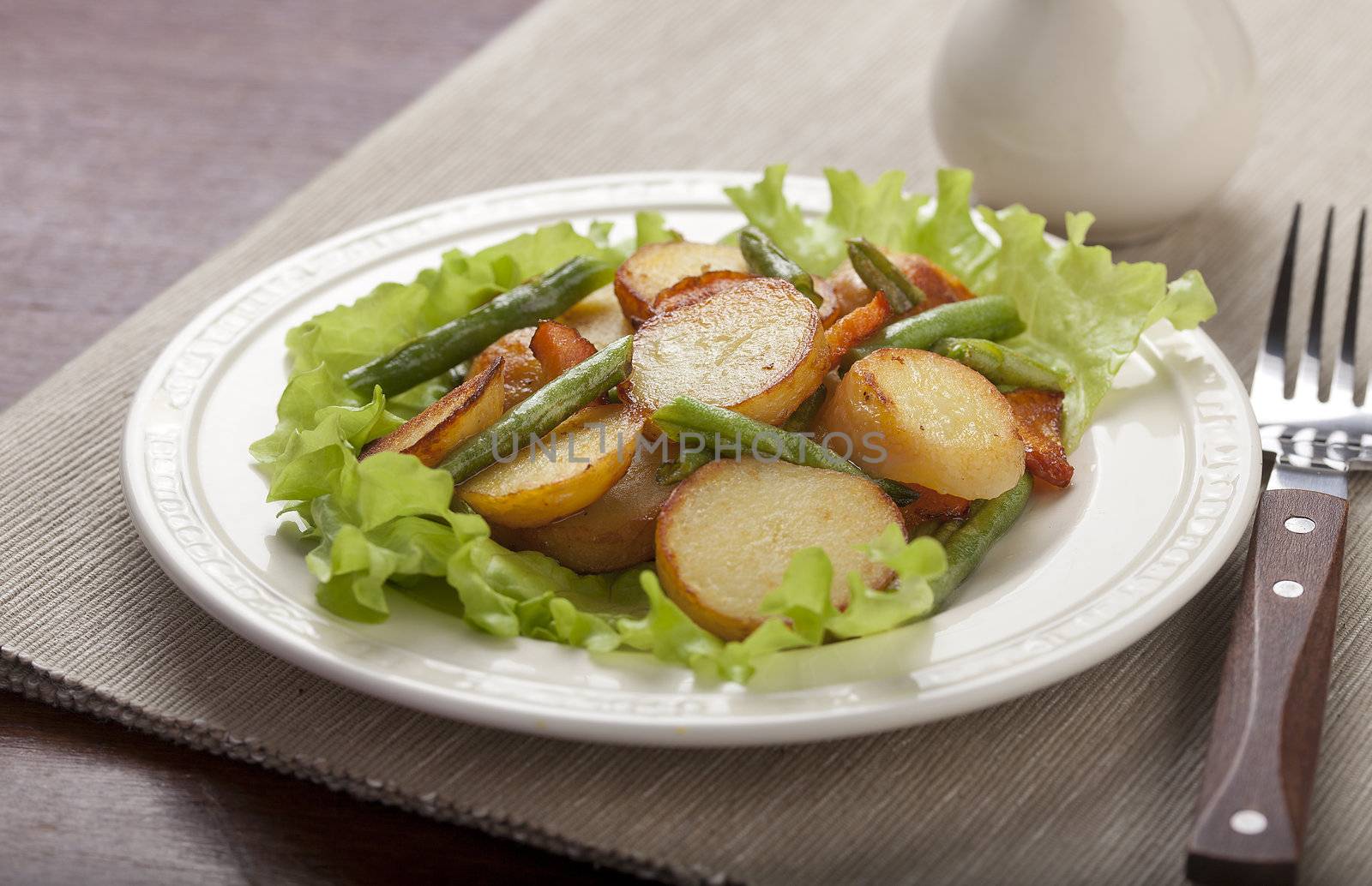 Fried potato, haricot and carrot with fresh lettuce on the white plate